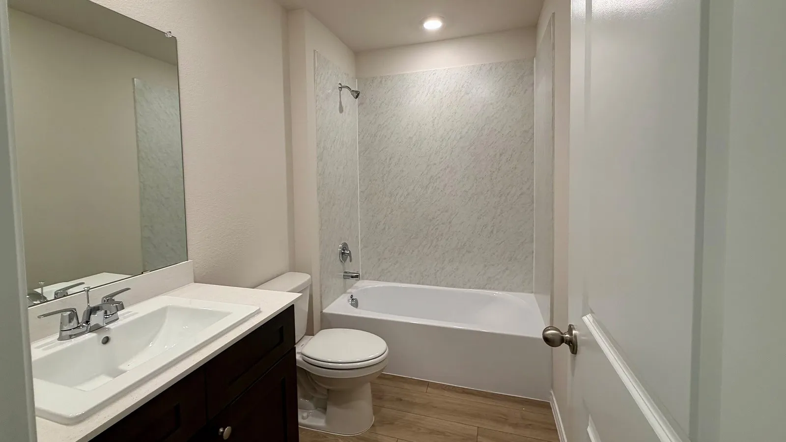 Modern bathroom featuring a dark vanity with an integrated sink and faucet, quartz countertop, large framed mirror, and recessed lighting