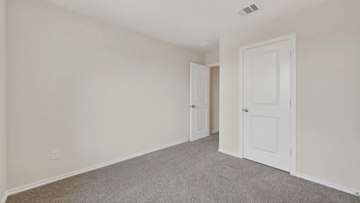 Neutral-toned interior room with gray flecked carpet and white baseboards