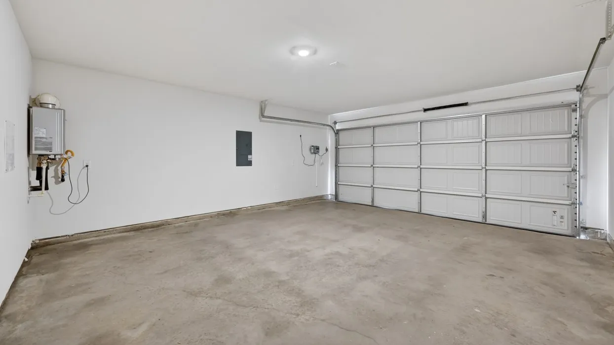 Spacious garage with a concrete floor, bright white walls, and a recessed ceiling light