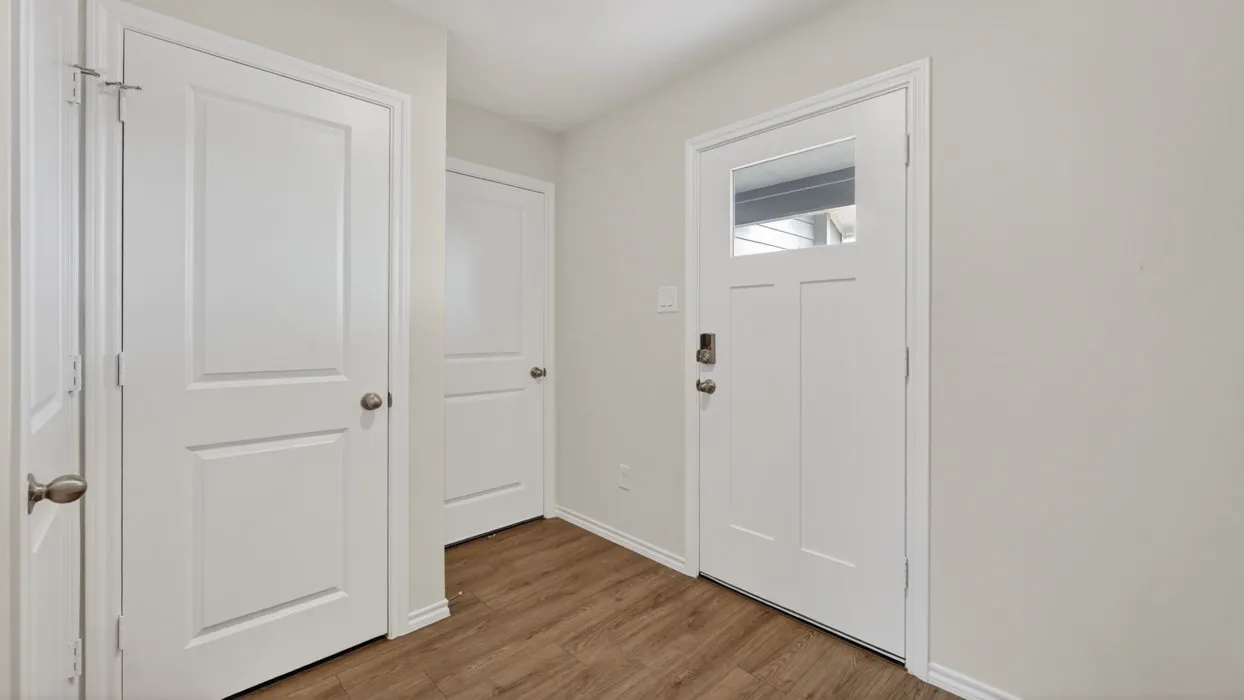 Entryway featuring a Craftsman-style door with upper lite, wood-finish flooring, white baseboards, and neutral wall paint