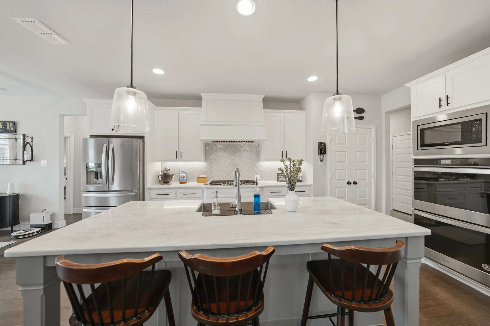 Large island, double ovens, gas range, herringbone backsplash, and farm house sink
