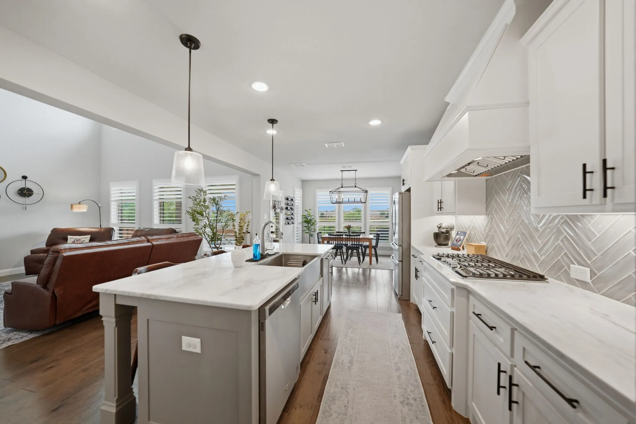 Herringbone backsplash, under counter lighting, farm house sink, gas range, and double ovens