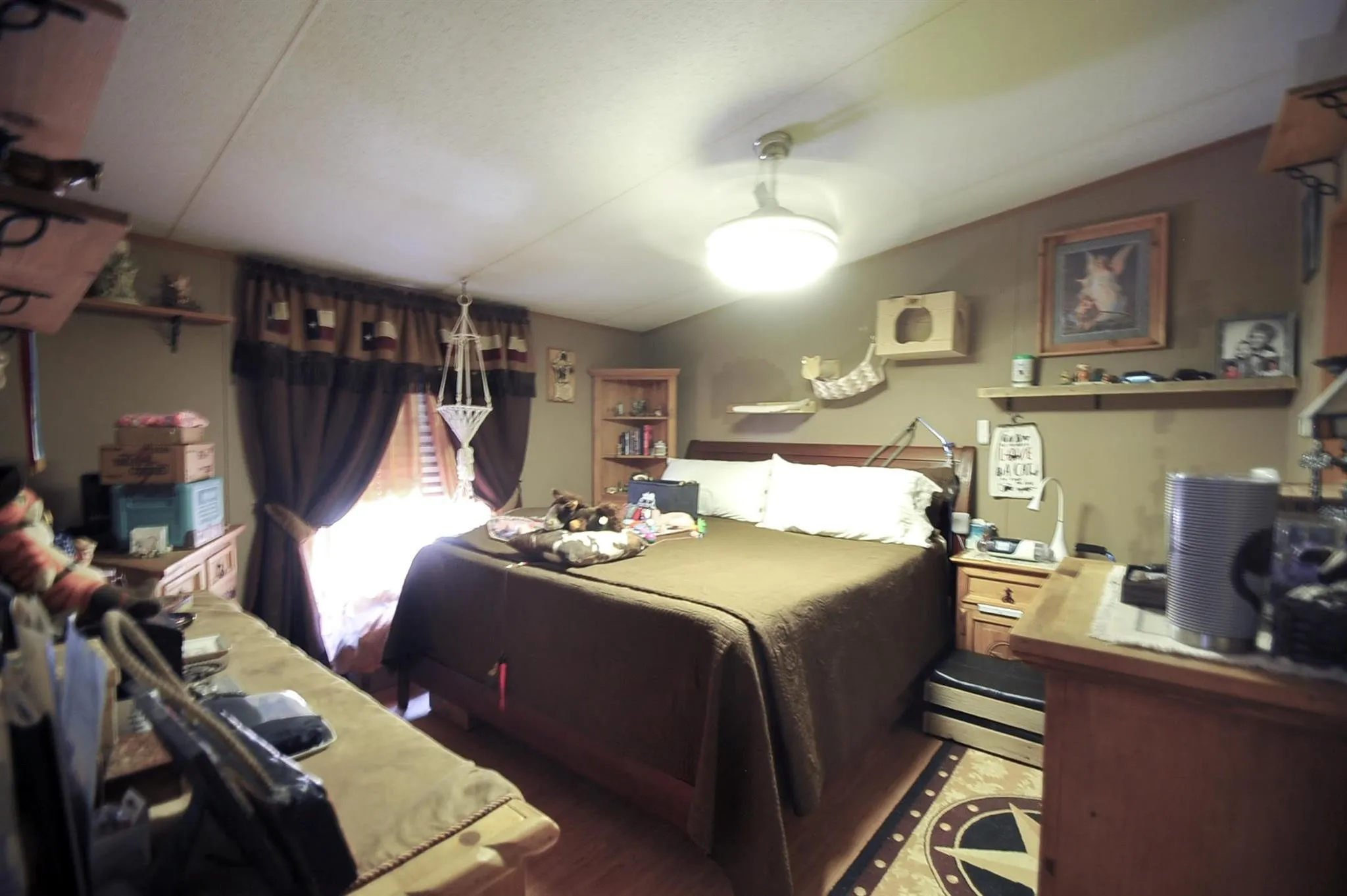 Bedroom featuring wood-finish flooring, a ceiling-mounted light fixture, and a window with dark curtains