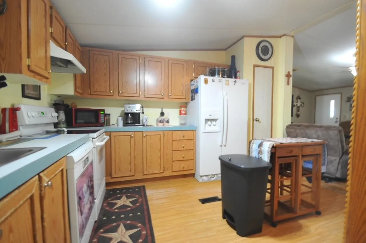 Kitchen featuring wood-finish cabinetry, light blue countertops, a white range with an overhead vent, and a side-by-side refrigerator