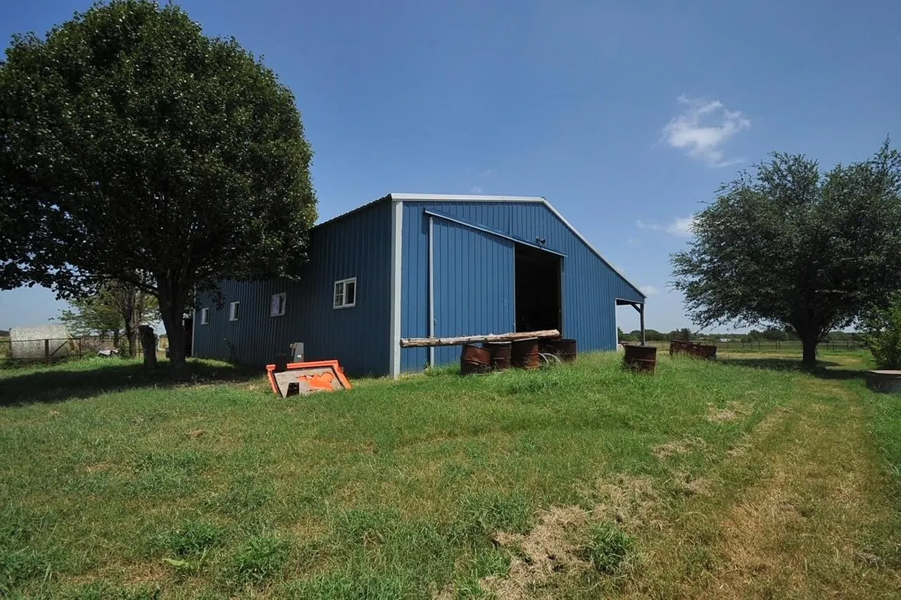 Expansive metal barn featuring a blue corrugated exterior and white trim