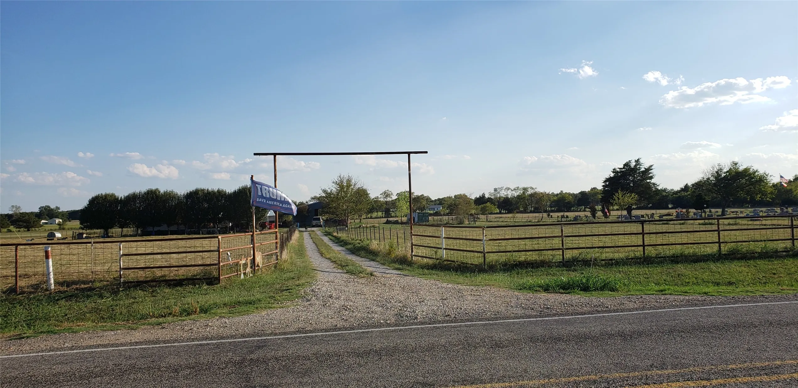 Gravel driveway extending through a metal gate entrance