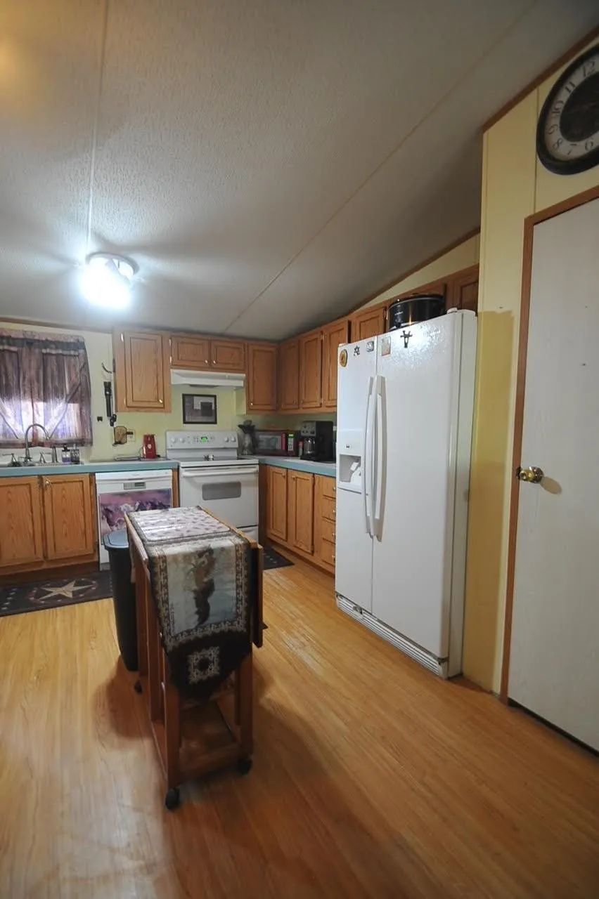 Kitchen featuring wood-finish flooring, wood cabinetry, and white appliances