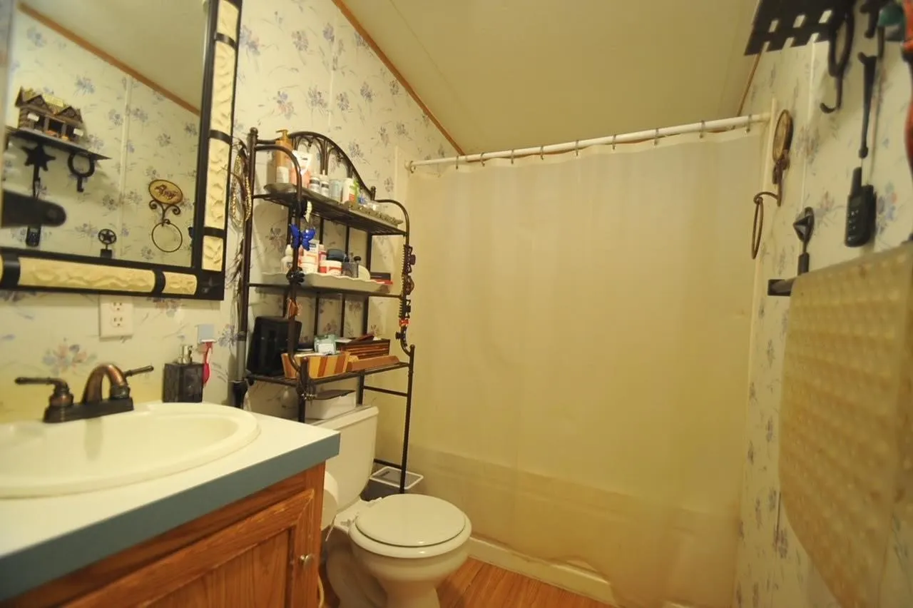 Bathroom featuring a single vanity with wood-finish cabinetry, a bronze-finish faucet, and an oval sink
