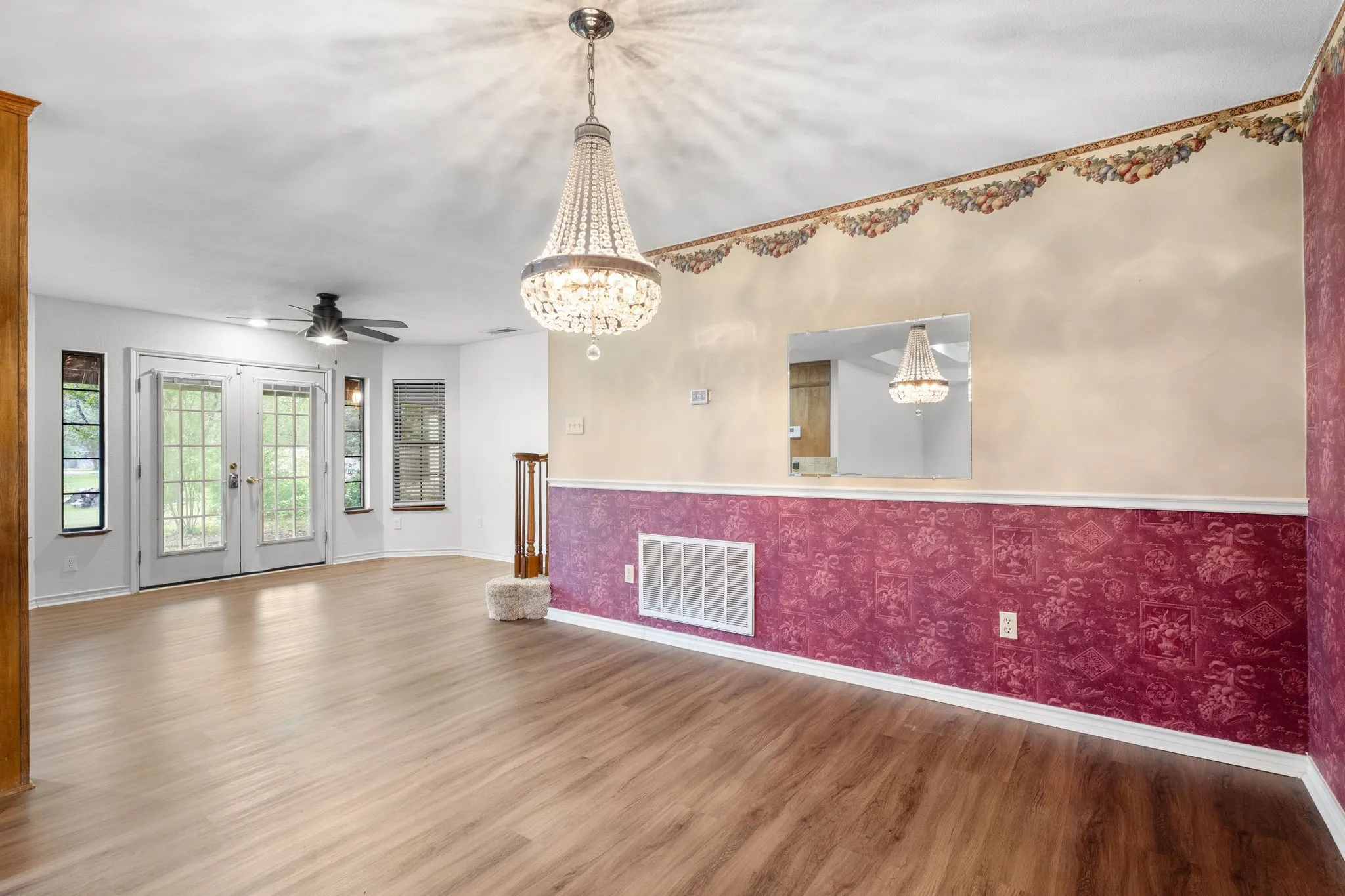 Open-concept room featuring wood-finish flooring, a tiered crystal chandelier, and a ceiling fan