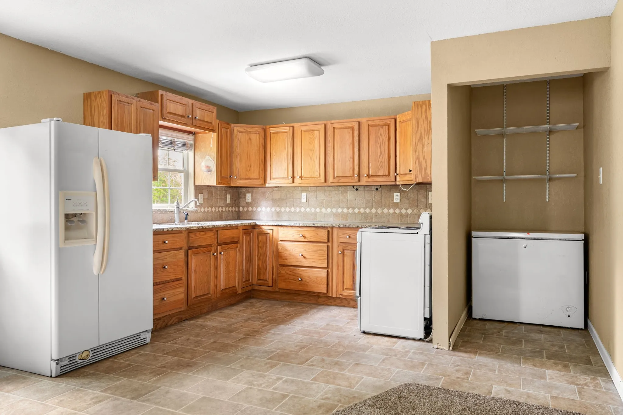 Kitchen featuring wood-finish cabinetry, tile flooring, and a patterned tile backsplash