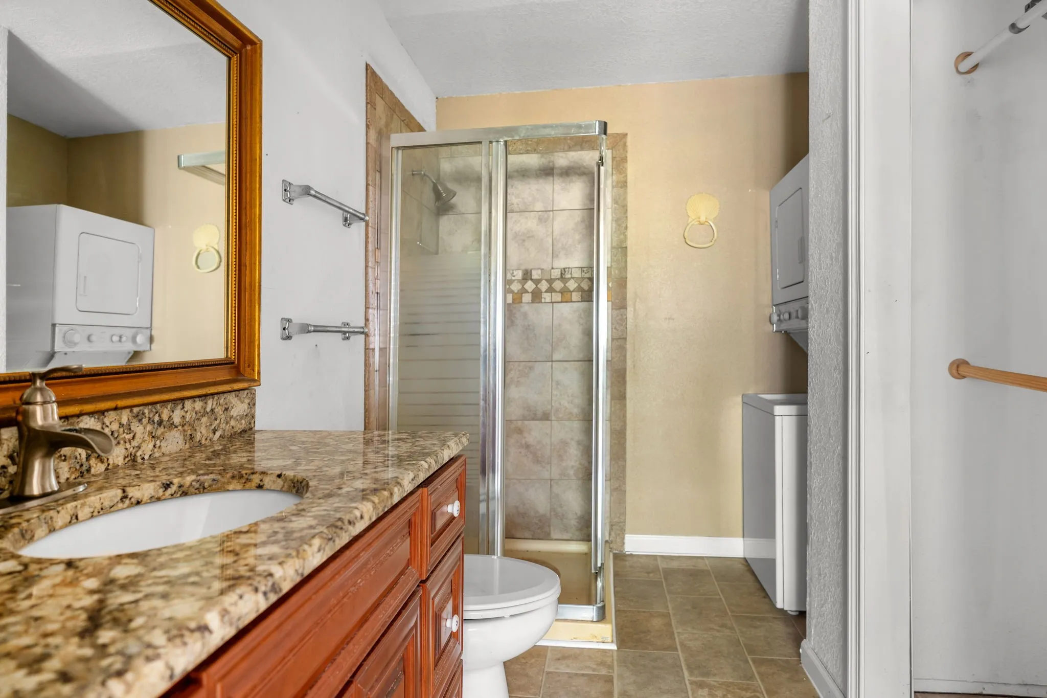 Bathroom featuring a wood-finish vanity with a granite countertop, undermount sink, and bronze-finish faucet