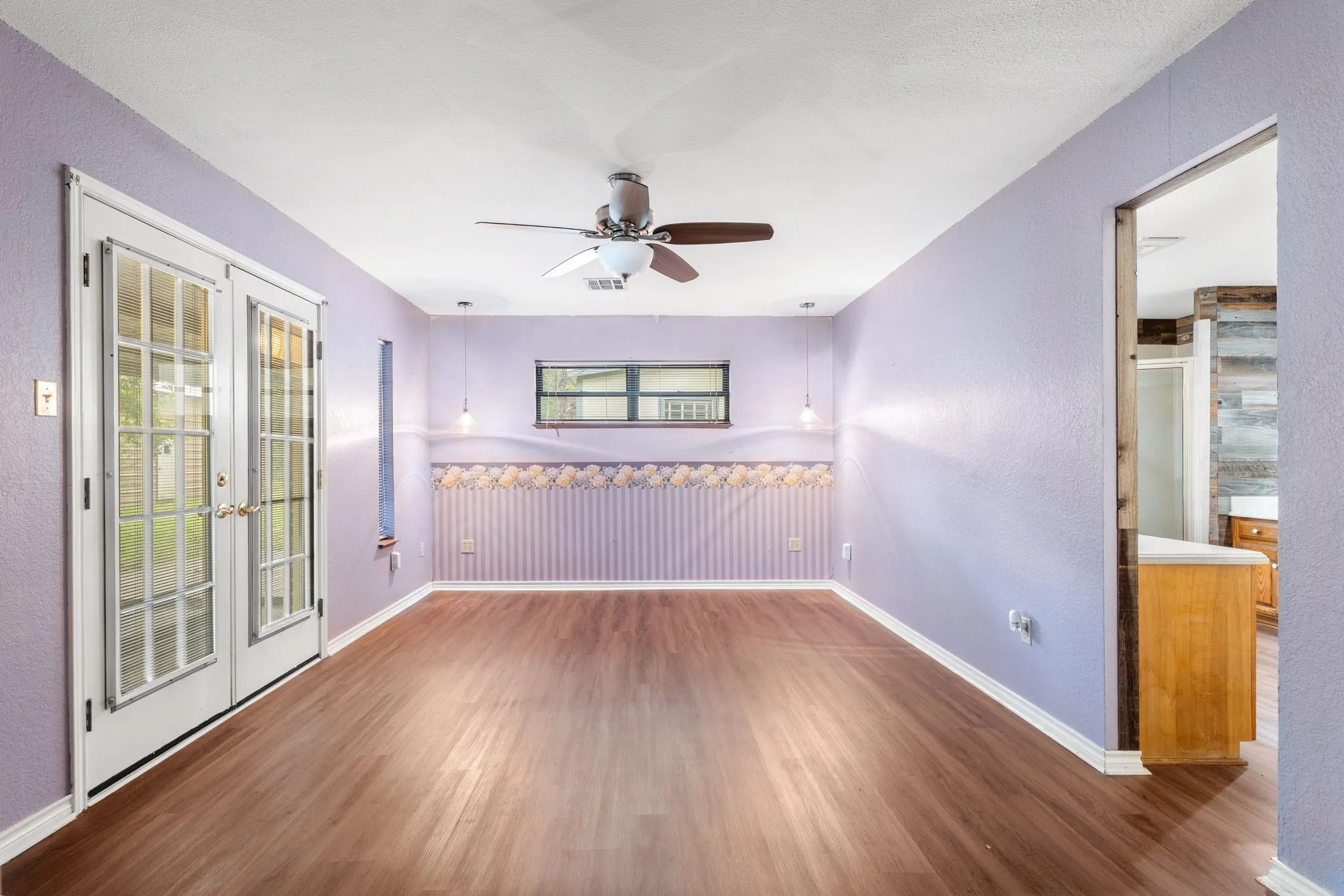 Room featuring wood-finish flooring, white trim, and a ceiling fan with integrated lighting