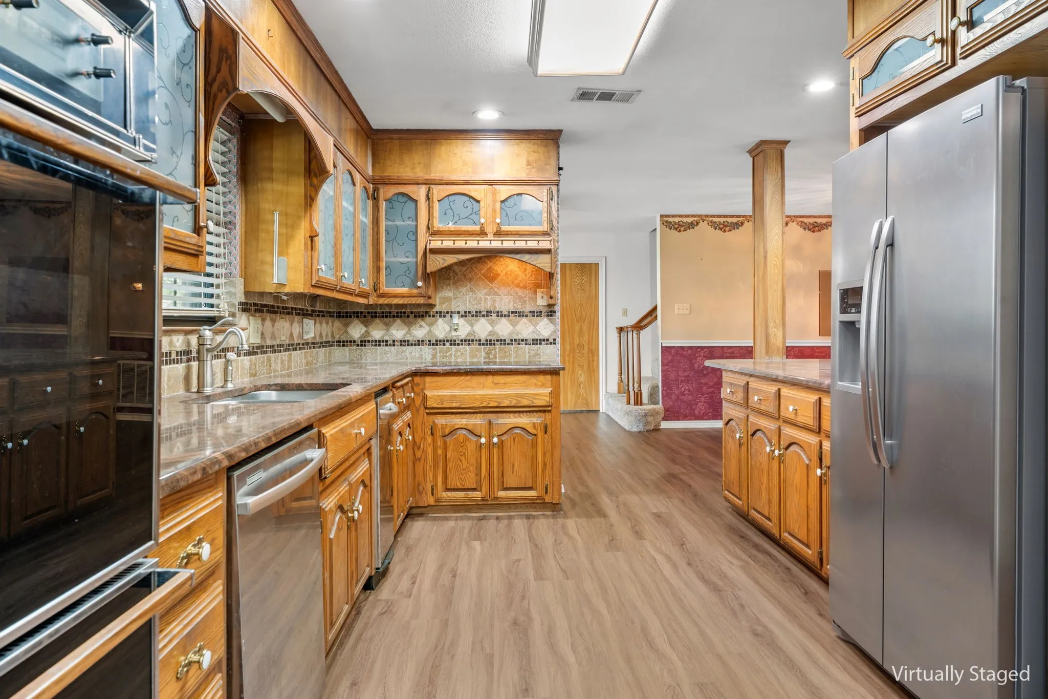 Kitchen featuring wood cabinetry, stainless steel appliances, and wood-finish flooring