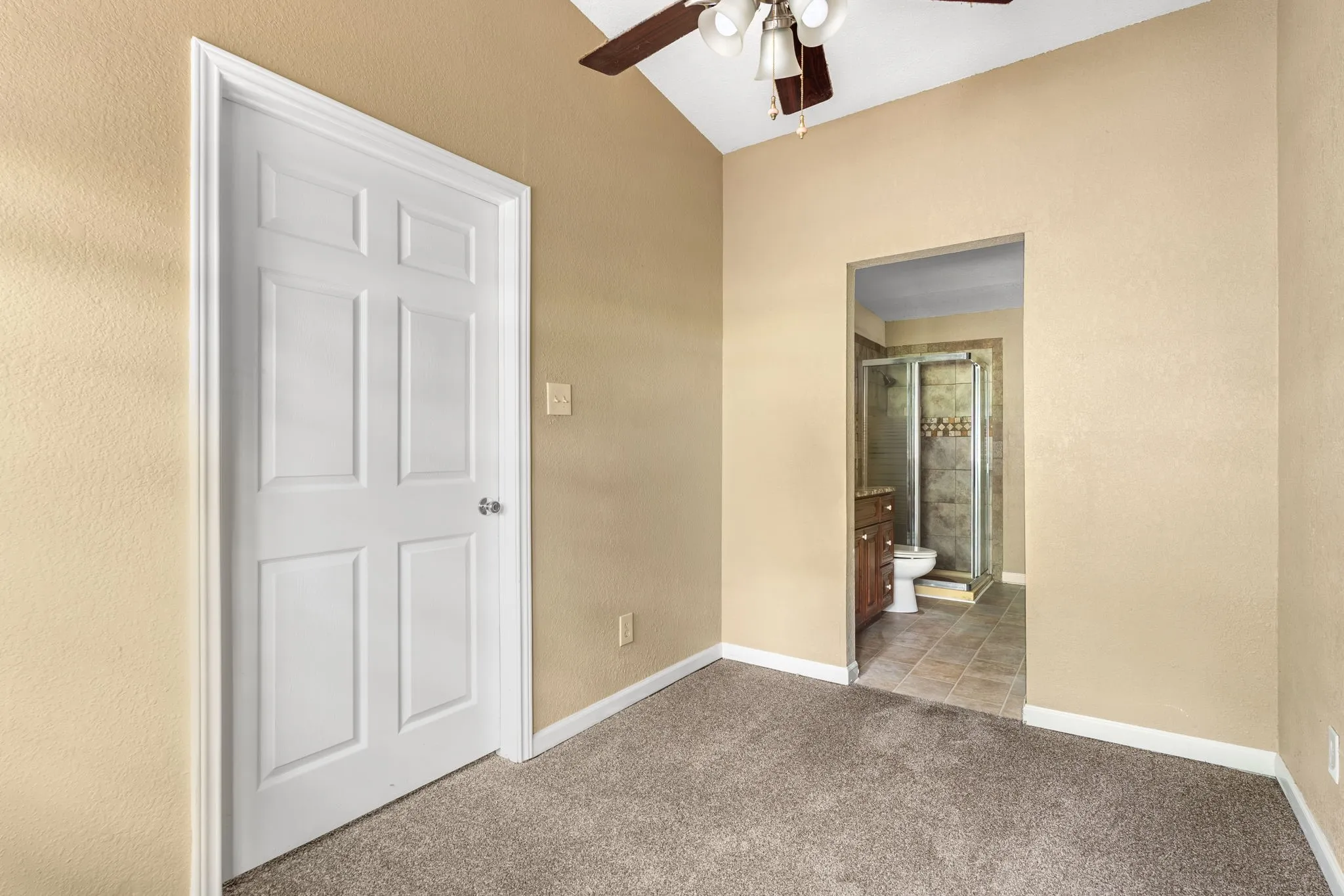 Carpeted room featuring a vaulted ceiling and a ceiling fan with light fixture