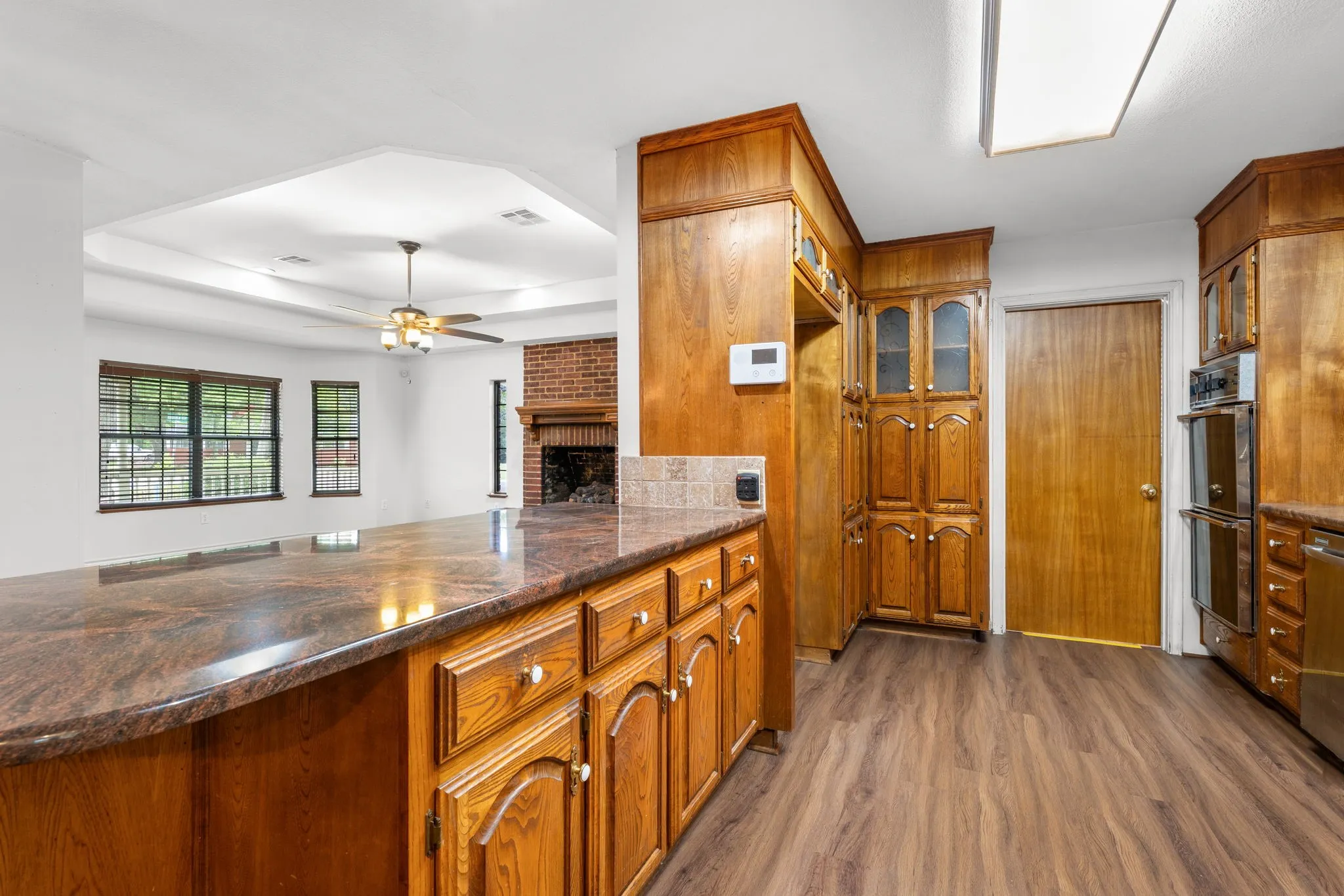 Kitchen featuring wood-finish cabinetry, a large peninsula with a speckled countertop, and wood-finish flooring