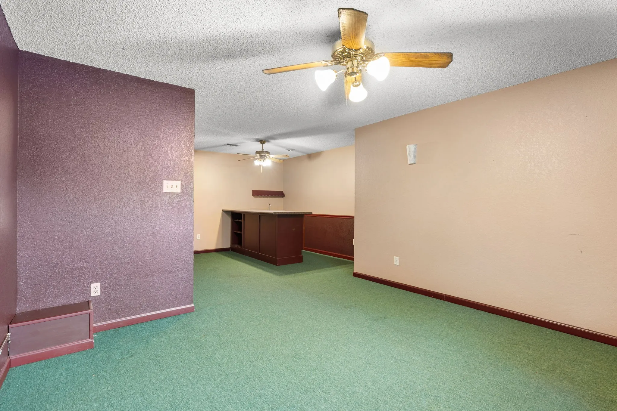 Spacious room with green carpet flooring and a built-in bar cabinet