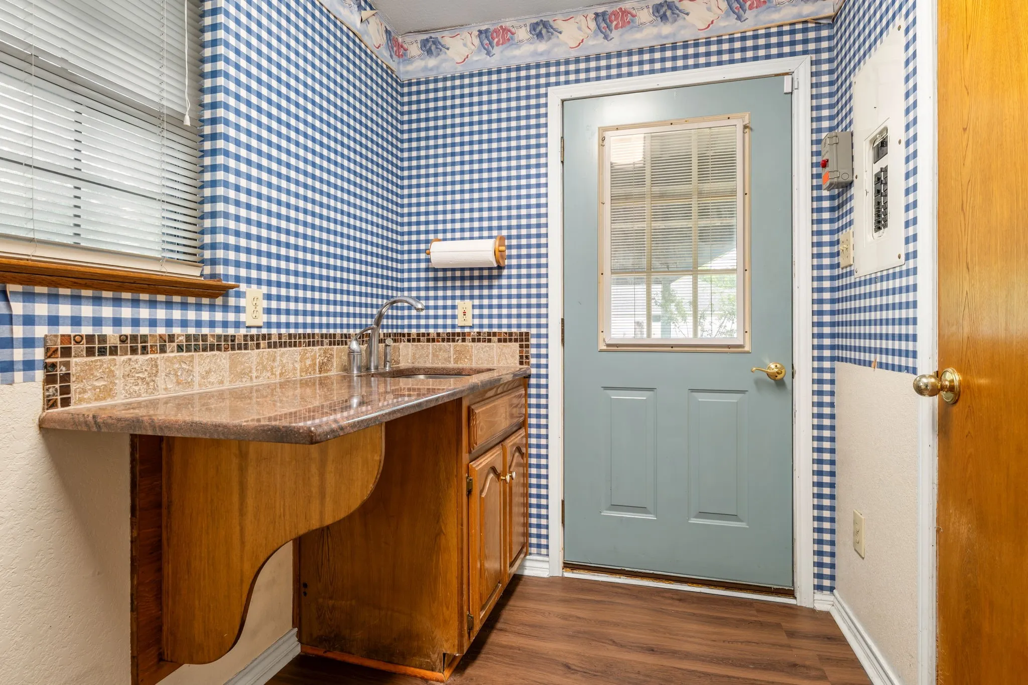 Utility area featuring a single basin sink with a contemporary faucet, wood-finish flooring, and a patterned tile backsplash