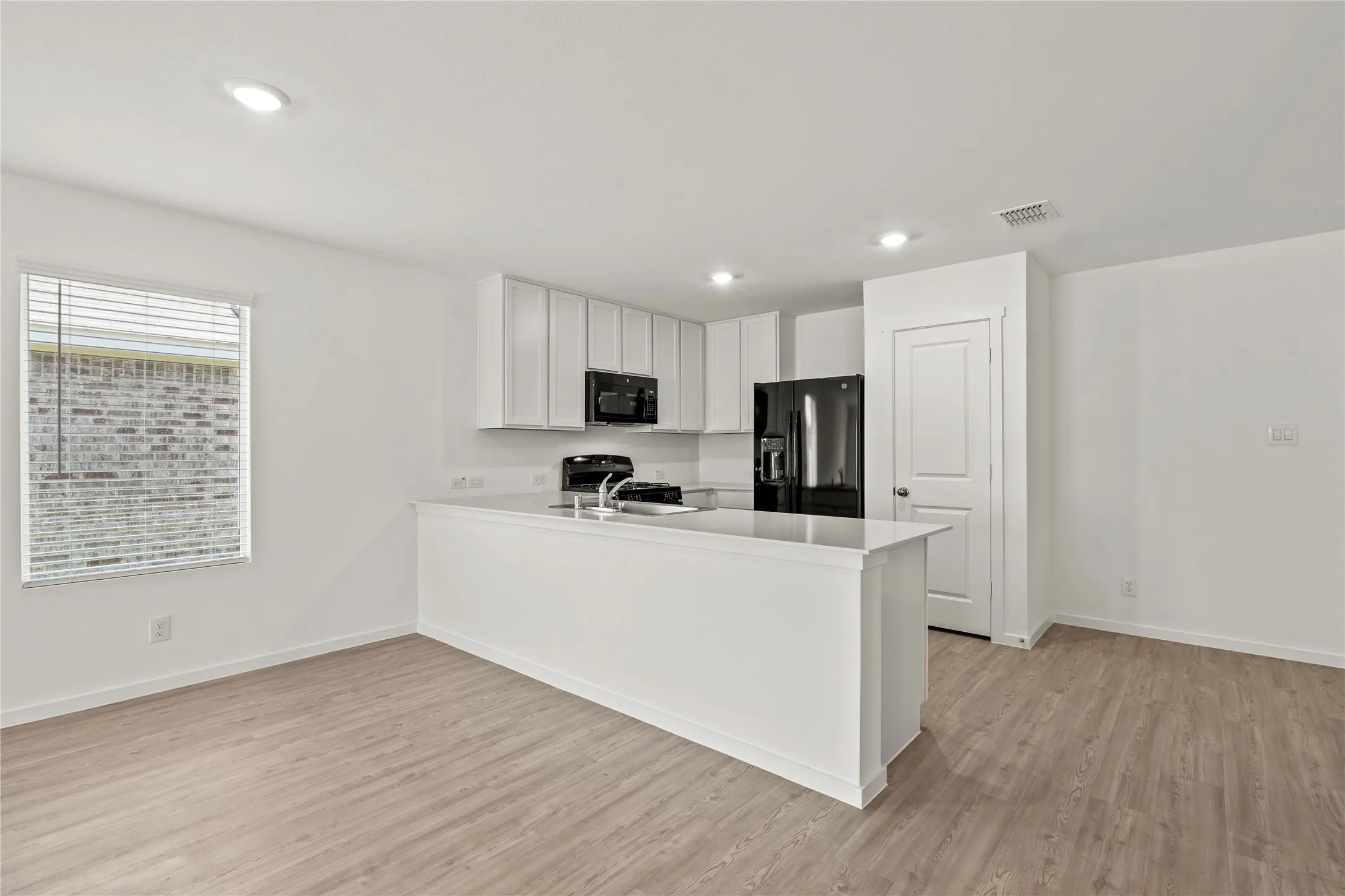Open-concept living area featuring wood-finish flooring and recessed lighting