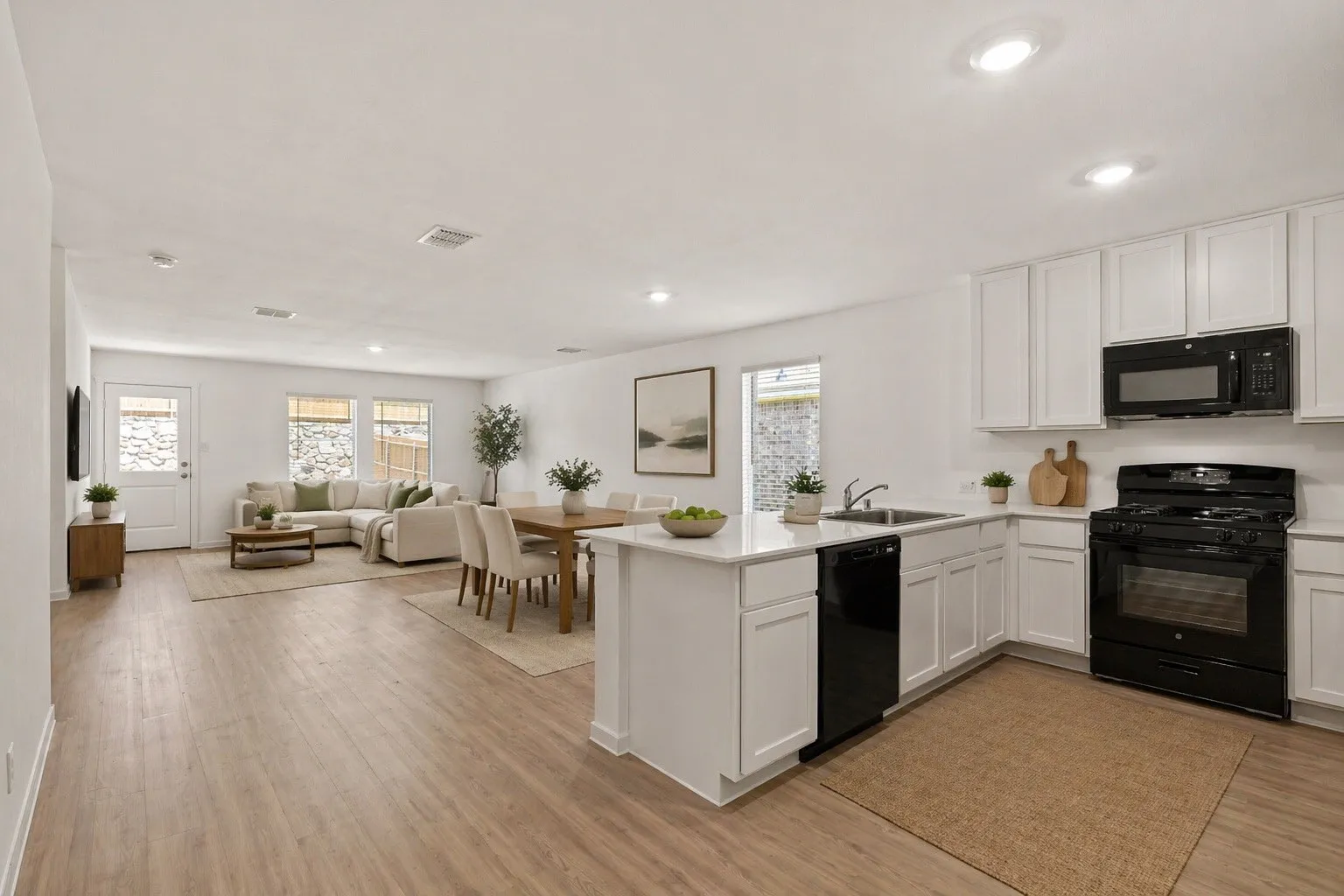 Open-concept living space featuring wood-finish flooring, recessed lighting, and white walls throughout