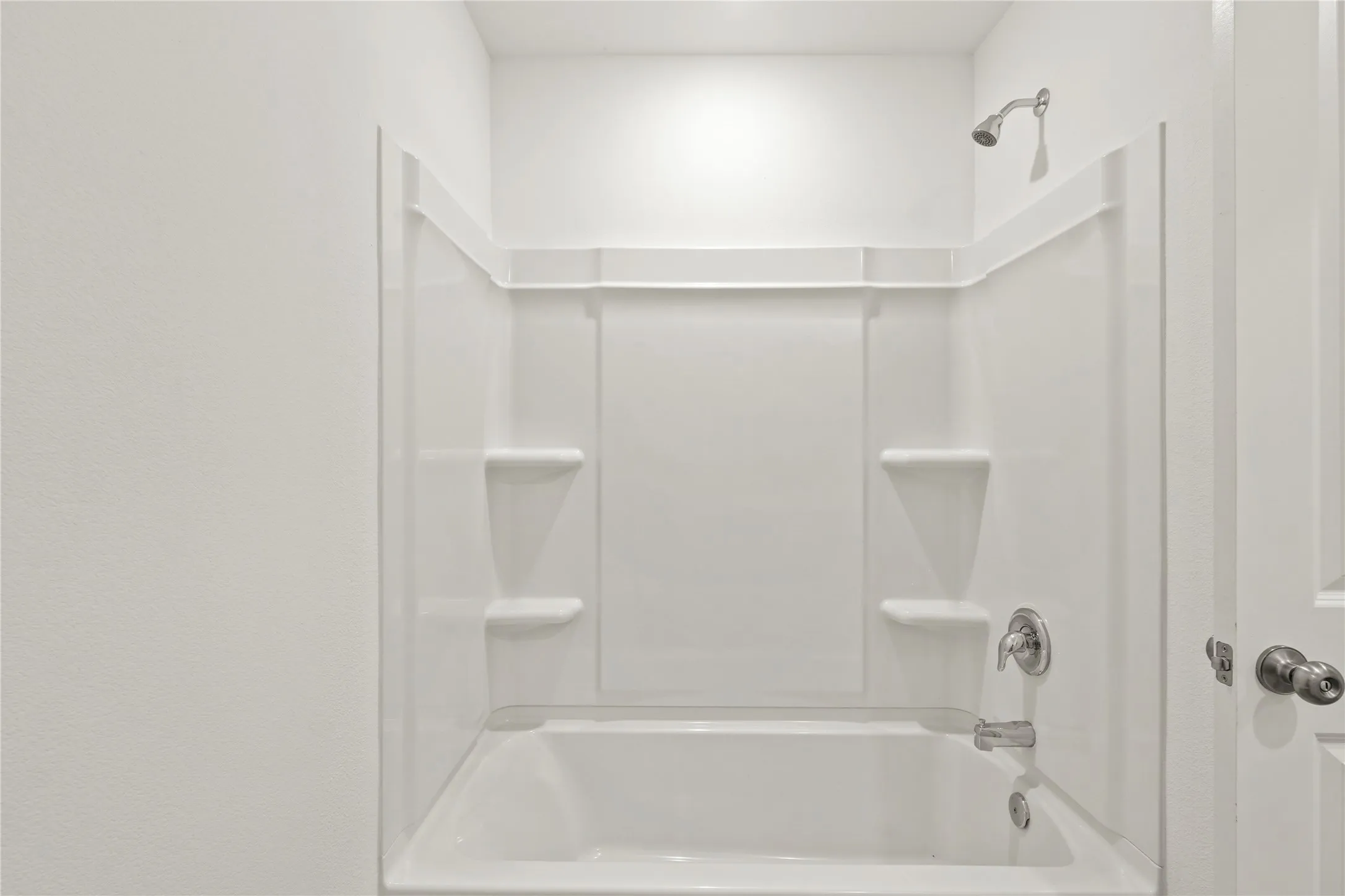Tub and shower combination featuring integrated shelving and a polished chrome fixture set