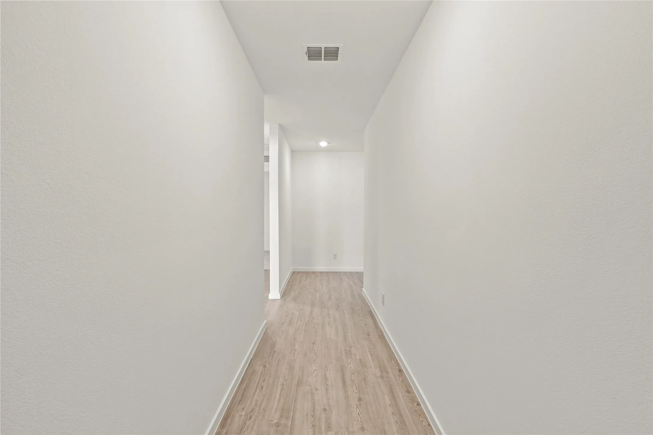 Hallway featuring wood-finish flooring, recessed lighting, and crisp white walls