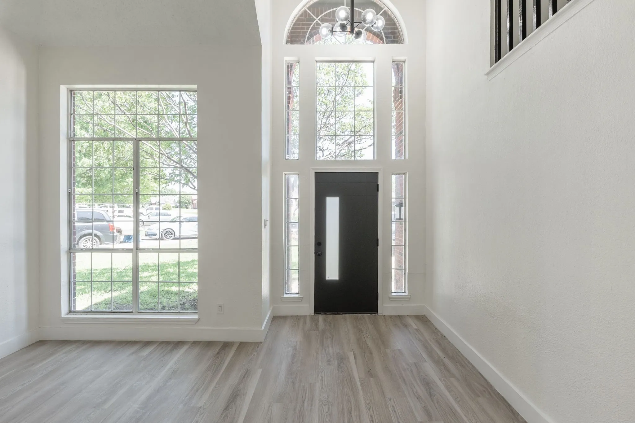 Two-story foyer featuring a black entry door with vertical glass insert, transom window, and side lite windows