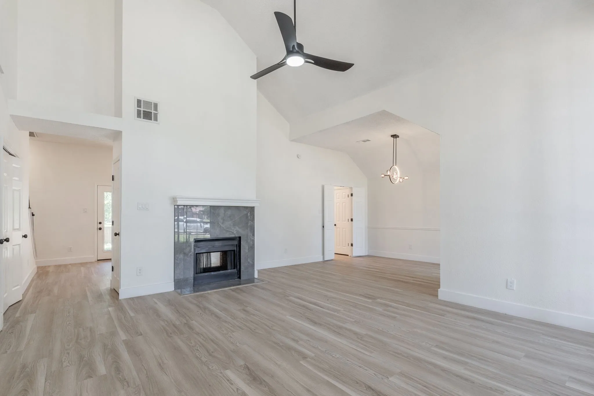Spacious living area featuring a vaulted ceiling, wood-finish flooring, and a contemporary ceiling fan
