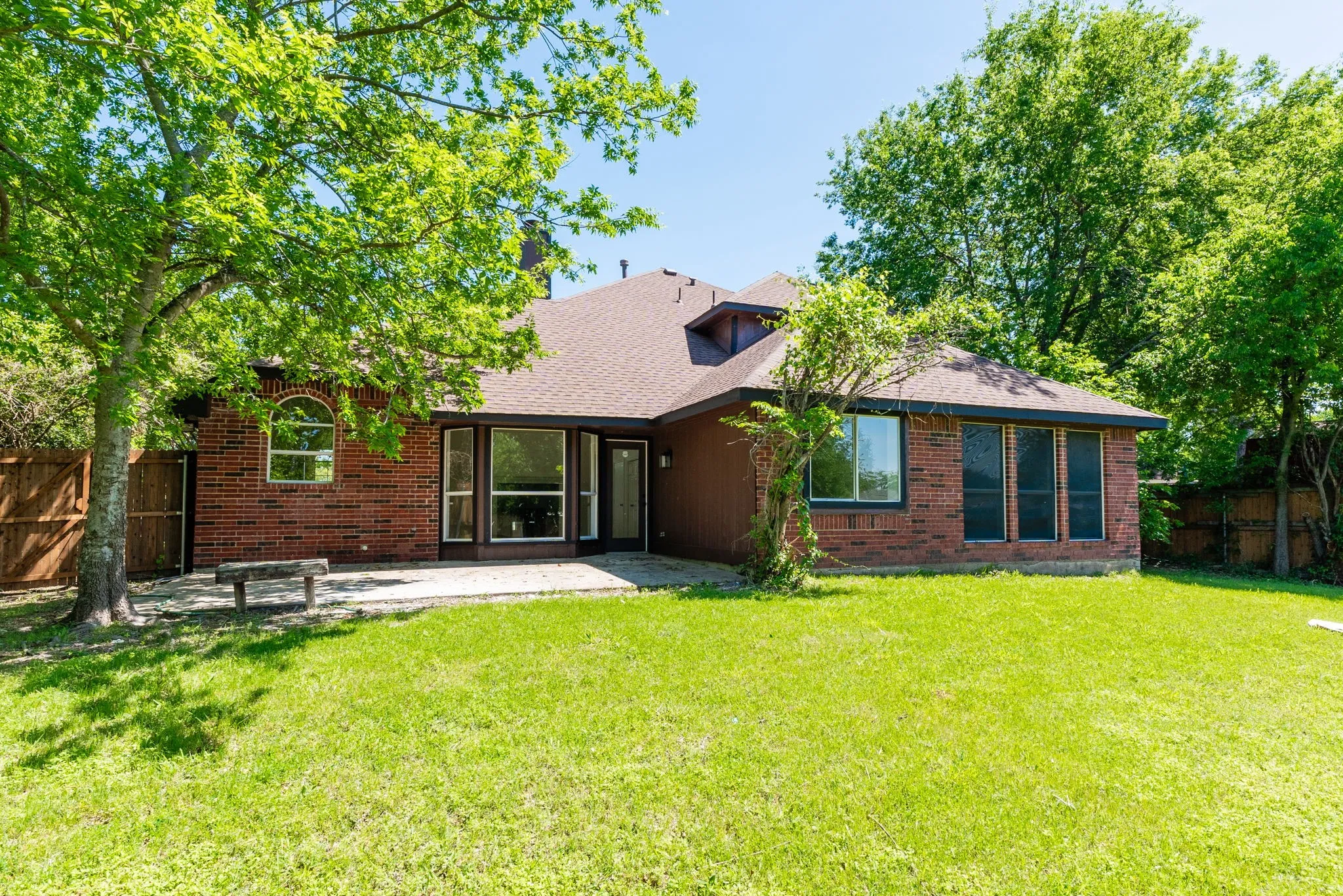 Expansive green lawn with a red brick exterior and mature trees