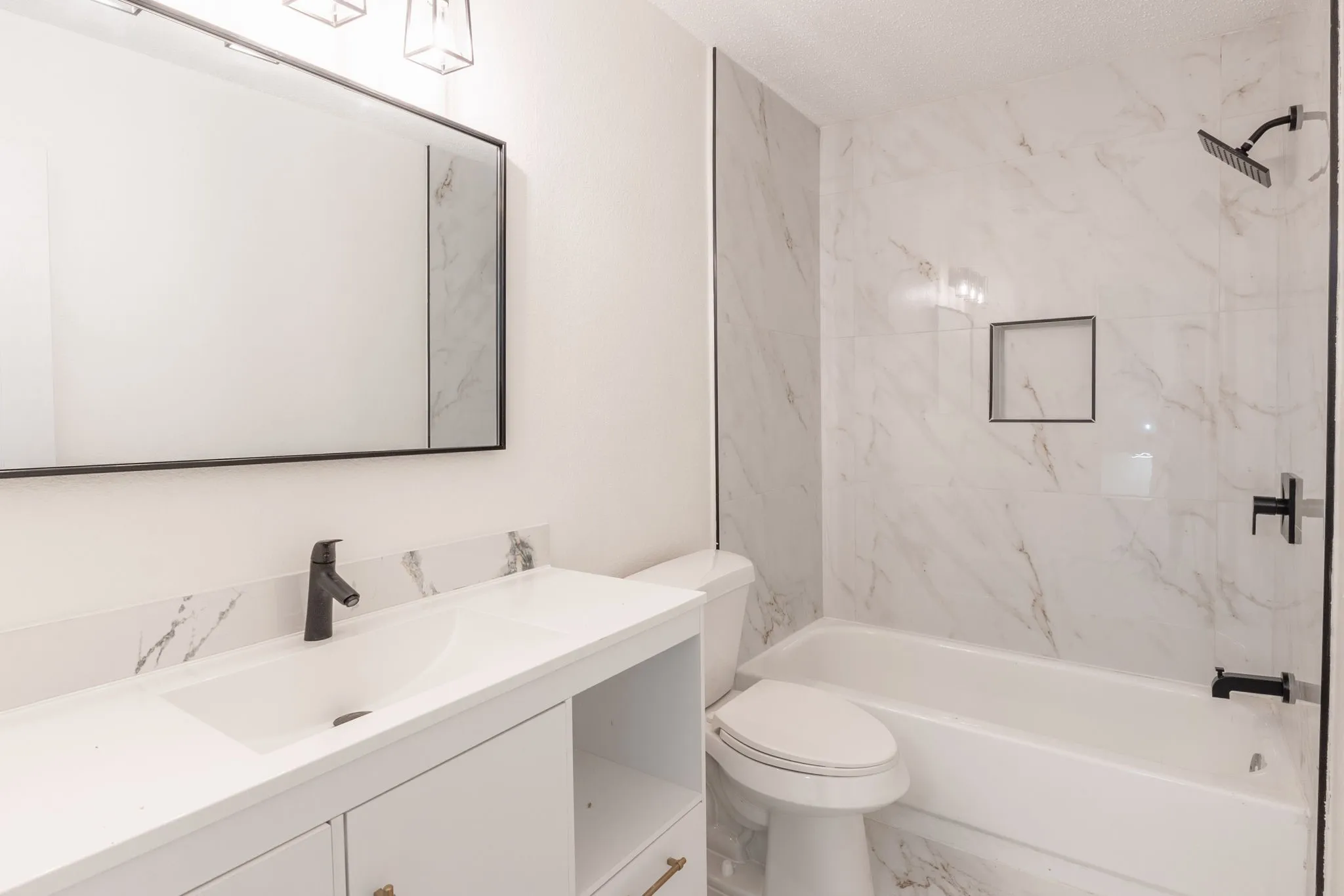 Bathroom featuring a white vanity with integrated sink, black matte faucet, and a large framed mirror
