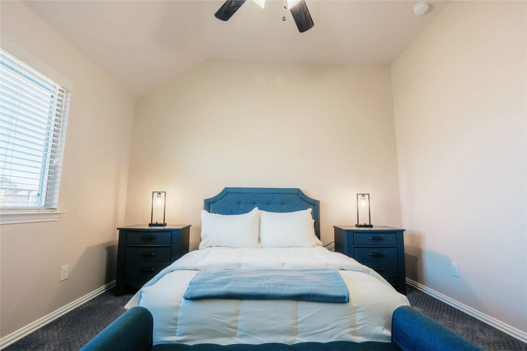 Neutral-toned room featuring a window with blinds, a ceiling fan, and carpeted flooring