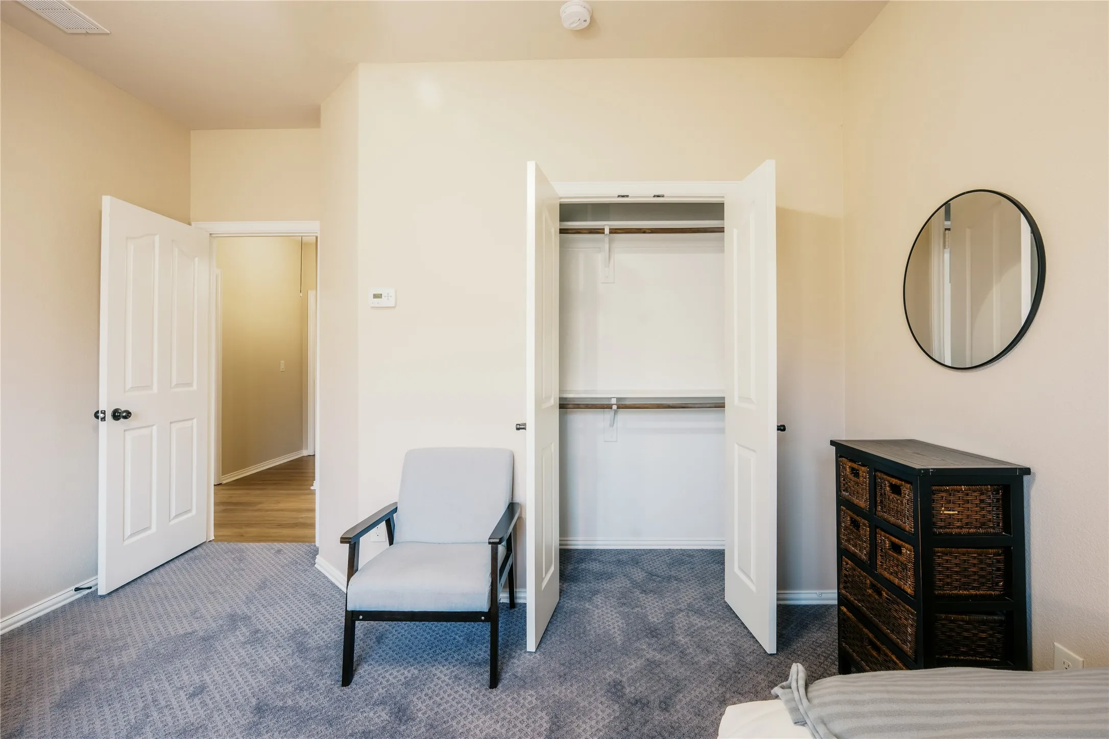 Bedroom featuring plush gray carpeting, neutral-toned walls, and a white paneled closet with shelving and hanging rods