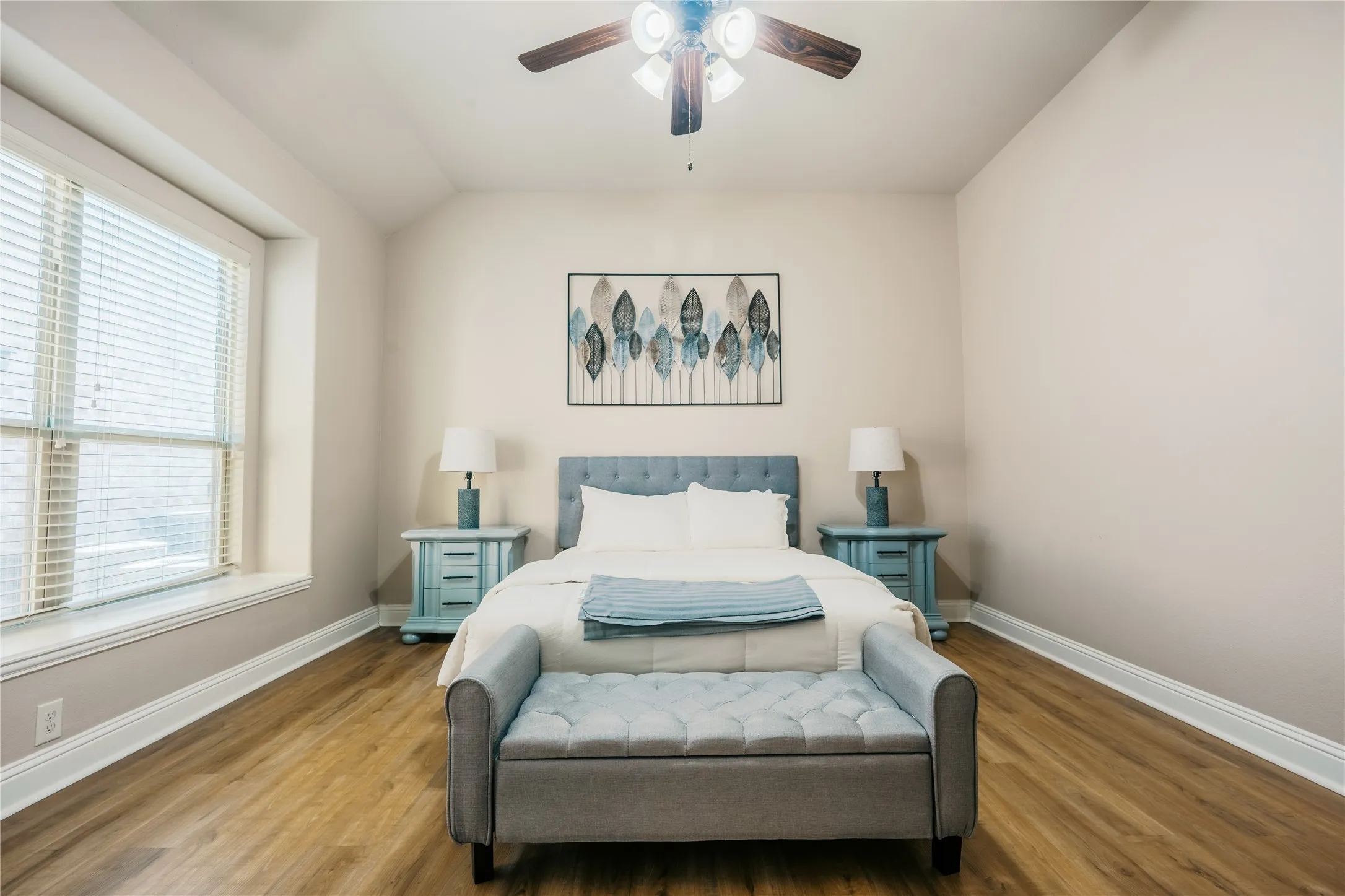 Room featuring wood-finish flooring, a ceiling fan with integrated lighting, and a large window with horizontal blinds