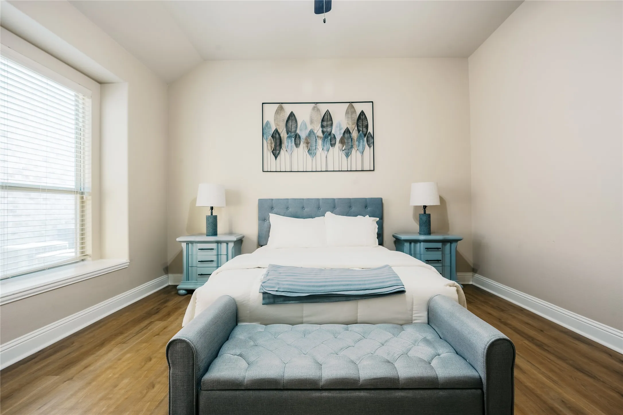 Bedroom featuring wood-finish flooring, a broad window with blinds, and light-toned wall paint
