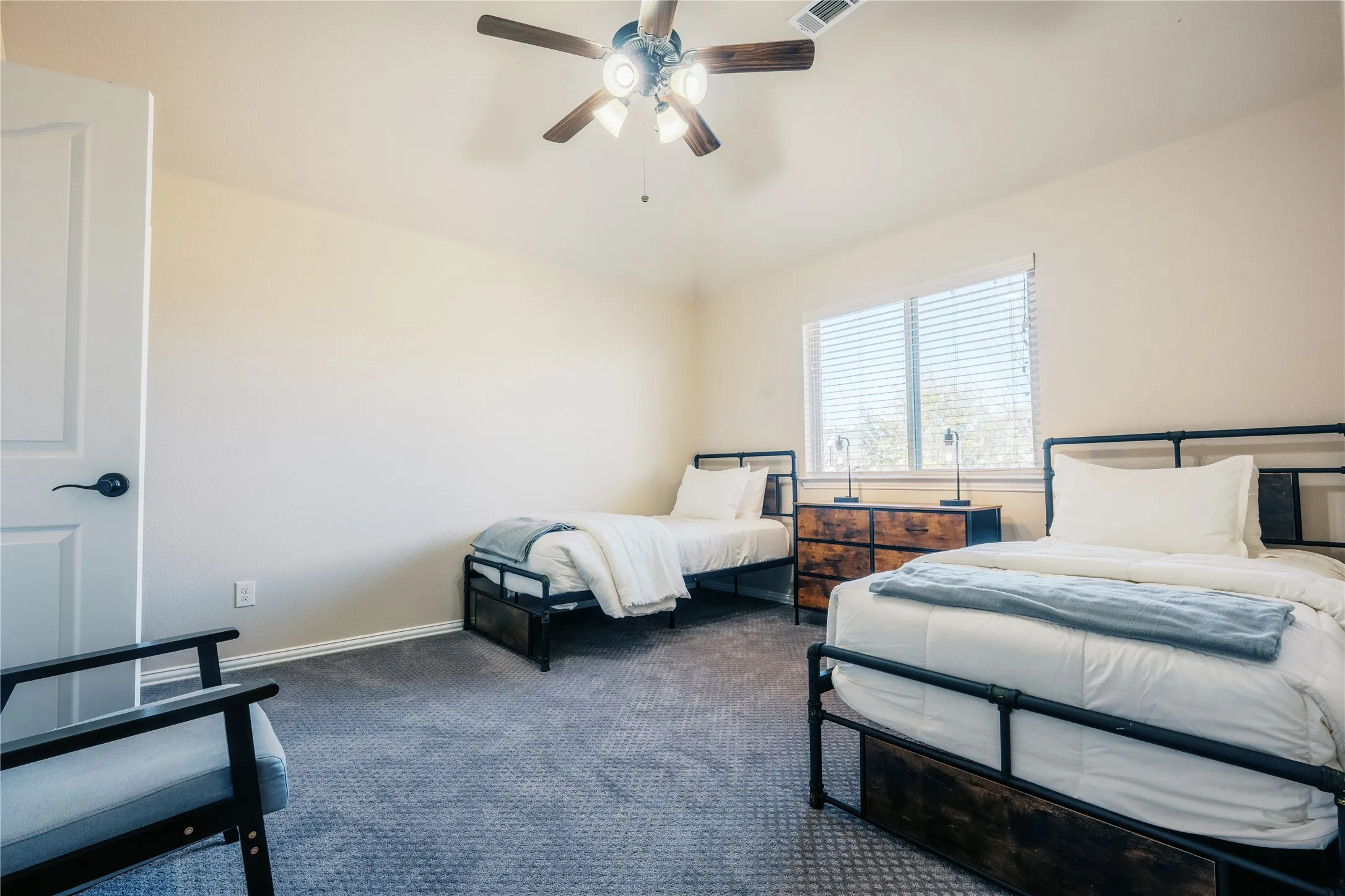 Spacious room featuring neutral-toned walls and grey patterned carpeting