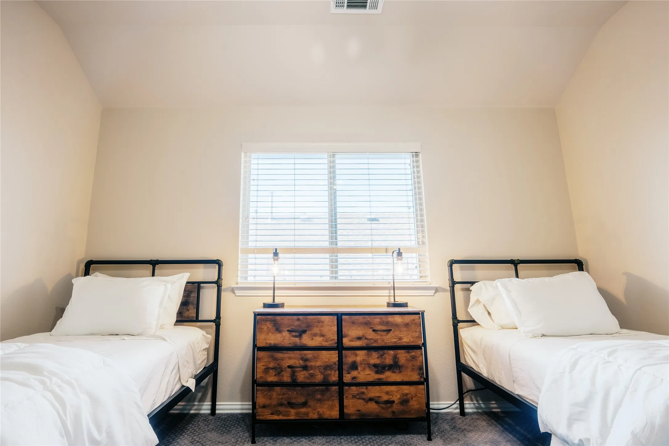 Bedroom featuring soft neutral wall tones and a single window with horizontal blinds