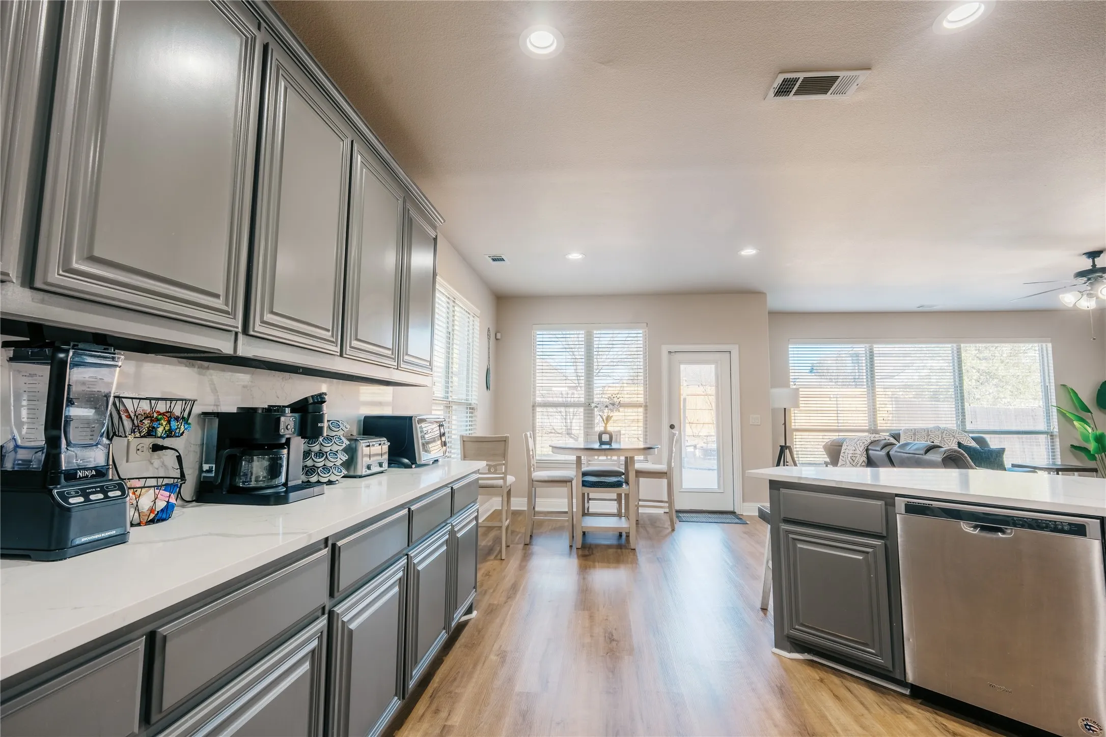 Well-appointed kitchen featuring extensive gray cabinetry, light-colored countertops, and wood-finish flooring