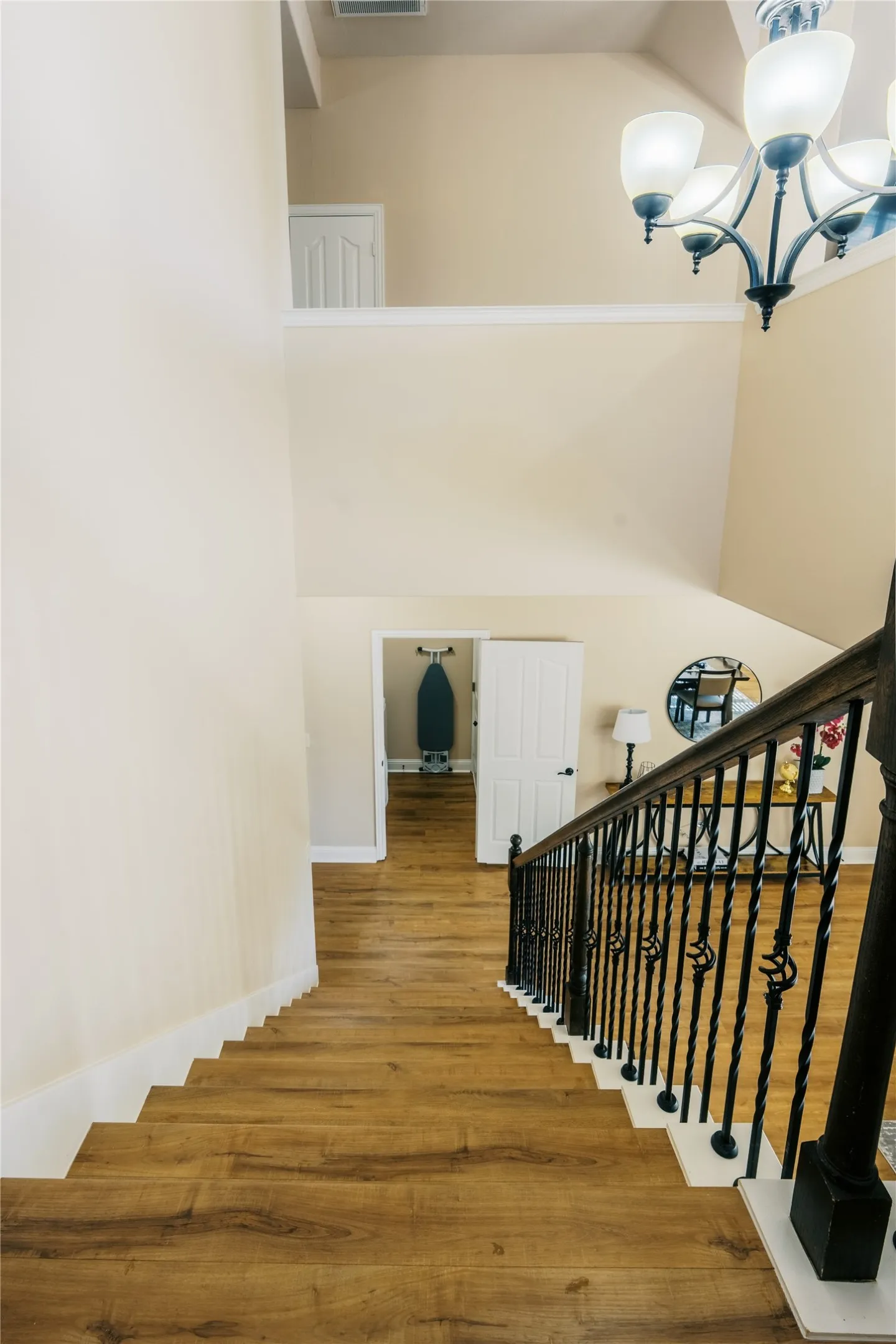 Staircase featuring wood-finish treads, white risers, and an ornate black metal railing with a dark wood-finish handrail