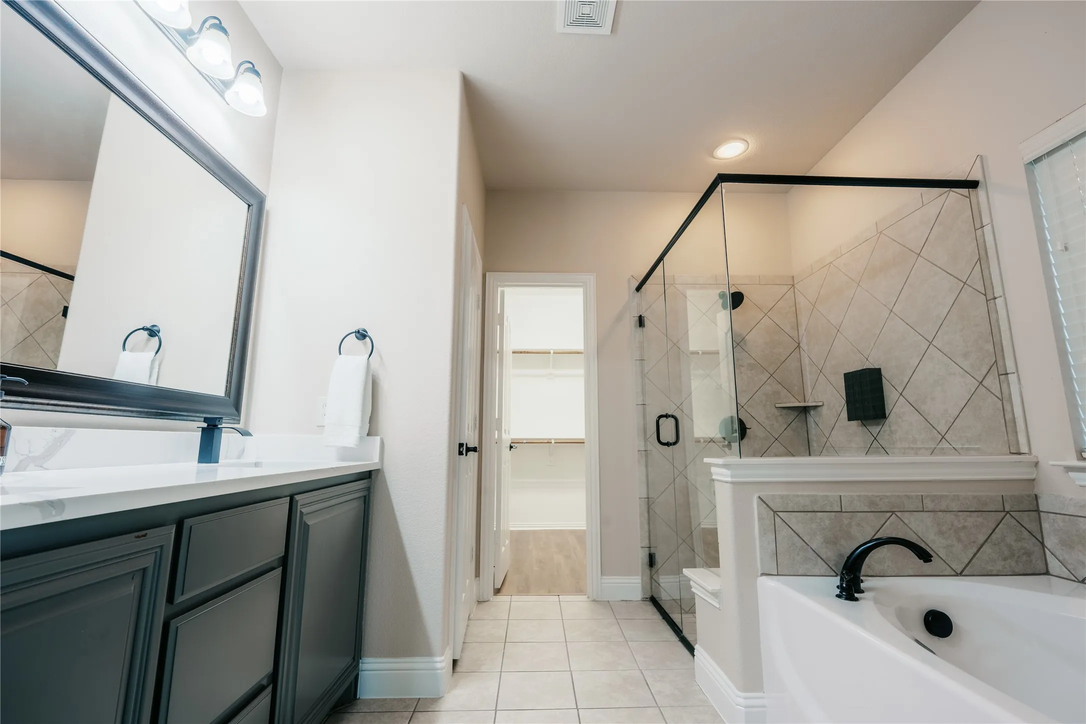 Bathroom featuring a dark wood vanity with a white countertop and framed mirror