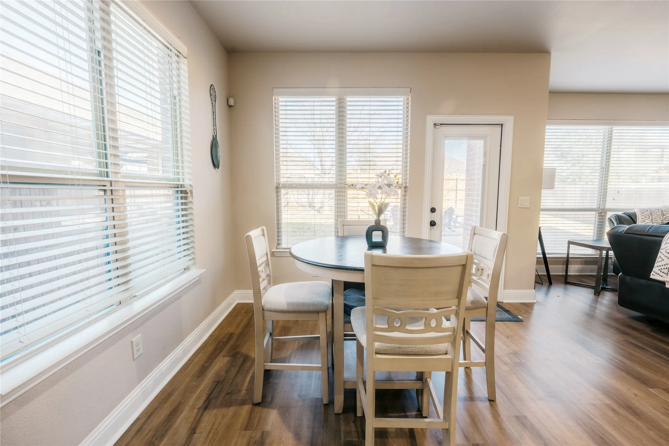 Dining area featuring wood-finish flooring, multiple windows with blinds, and light-toned walls
