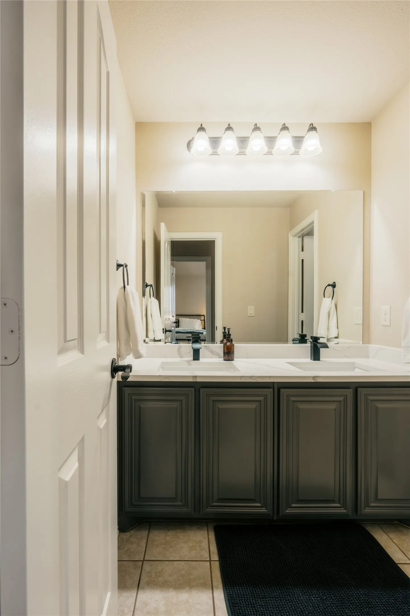 Double vanity with integrated sinks, dark grey cabinetry, white countertop, and black fixtures