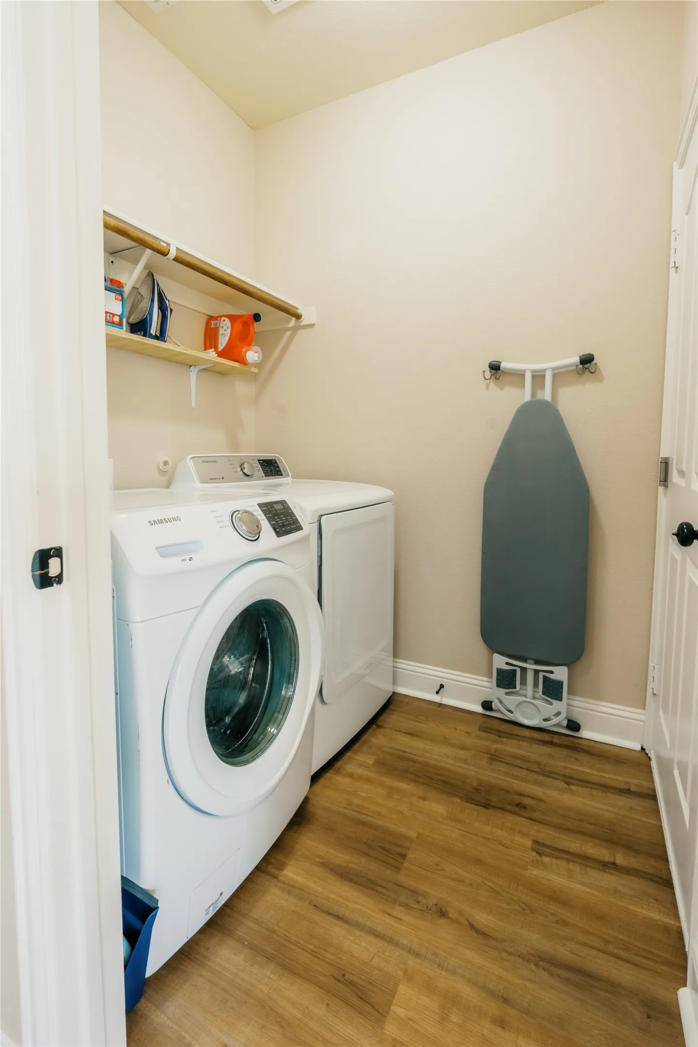 Dedicated laundry area featuring wood-finish flooring, white baseboards, and neutral wall paint