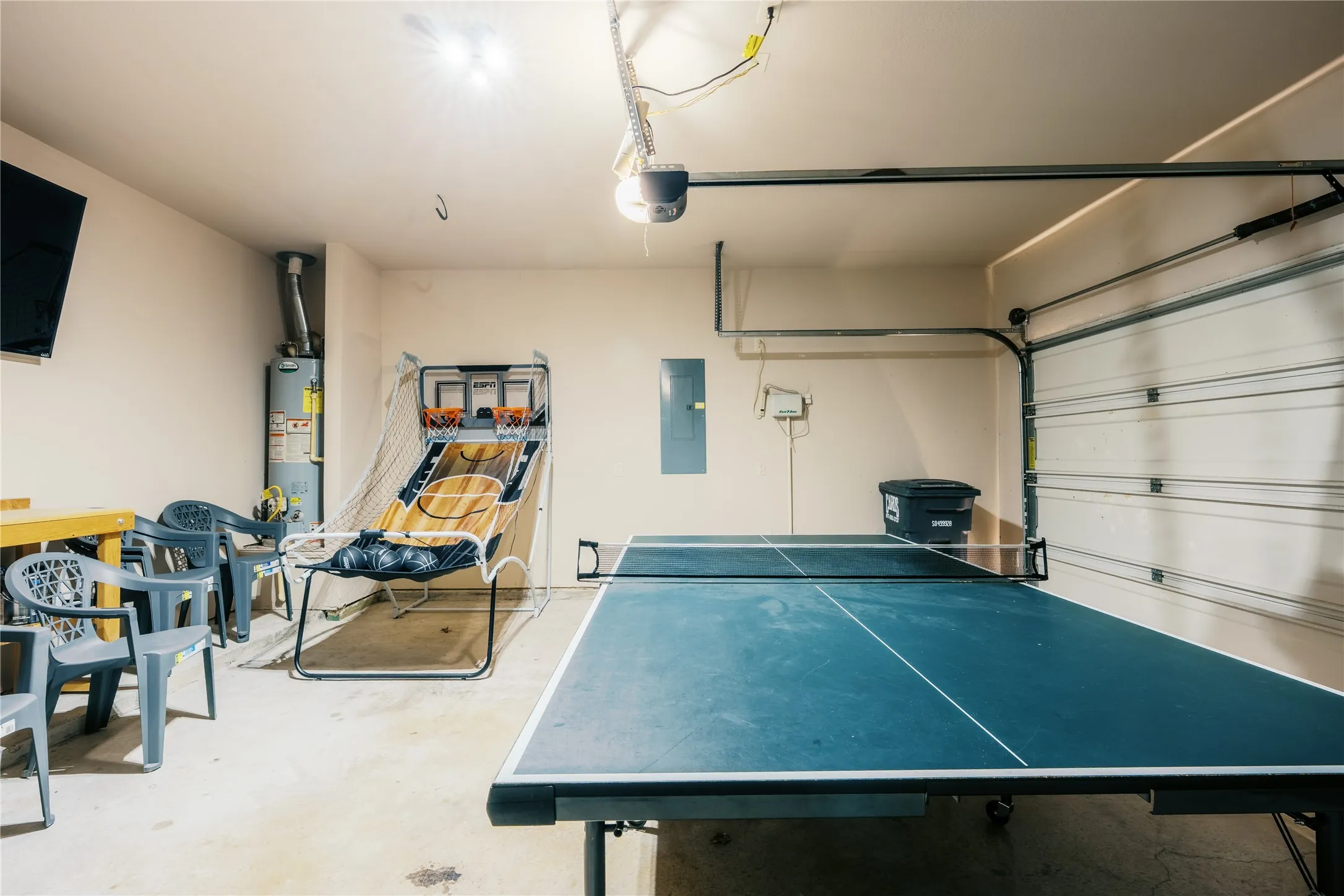 Utility space featuring concrete flooring, a side-hinged garage door, overhead lighting, and a water heater