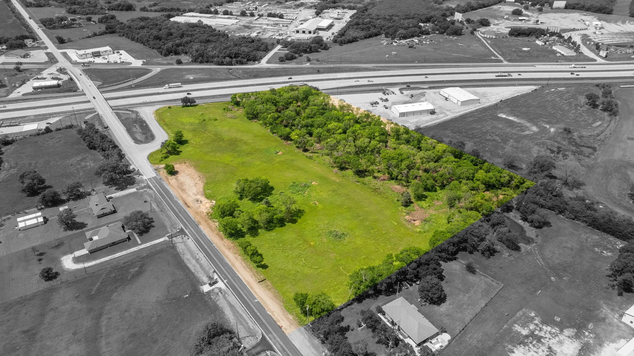 Expansive undeveloped parcel featuring a mix of open green space and mature tree cover