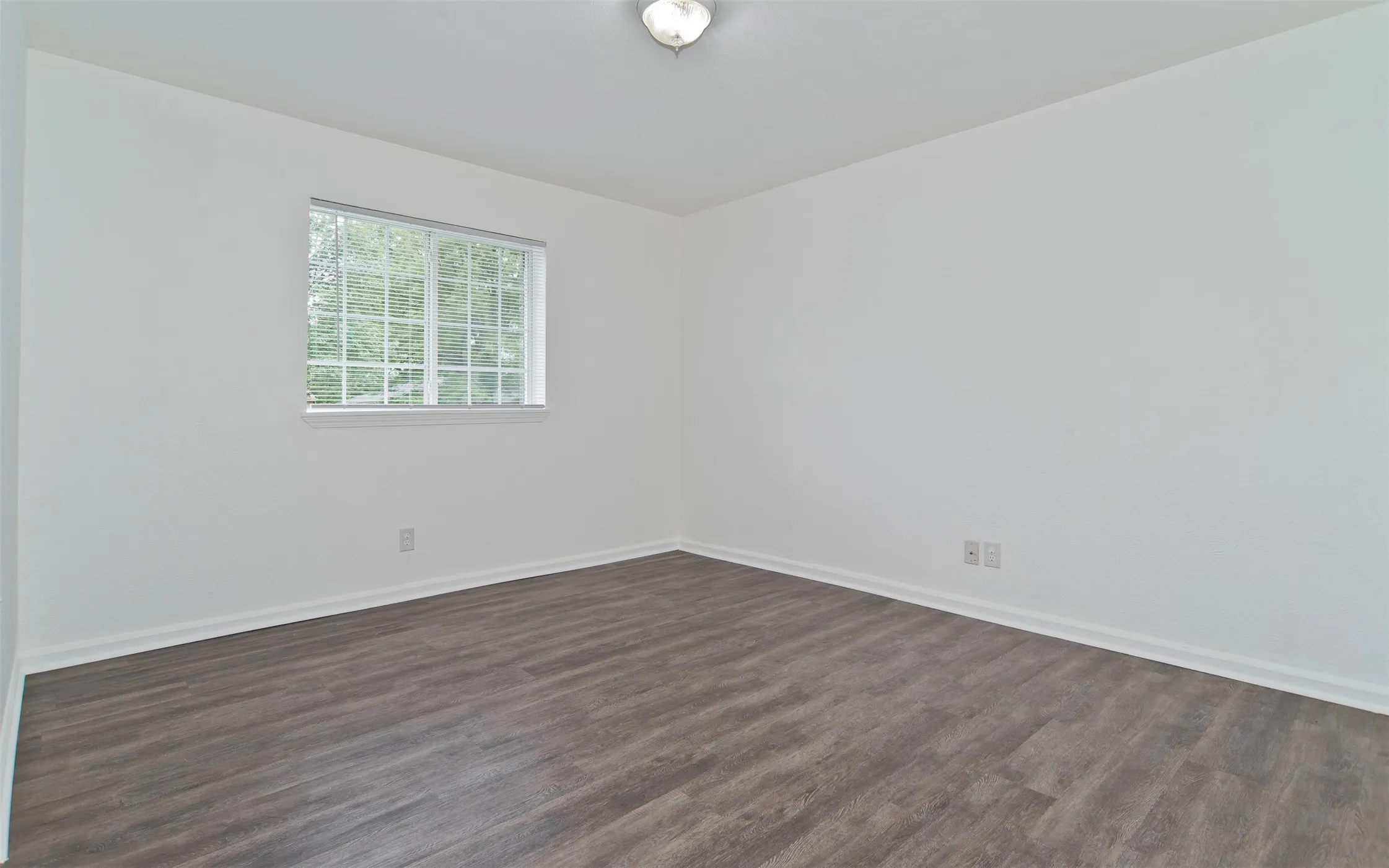 Room with wood-finish flooring, white walls, and a window with grid detailing