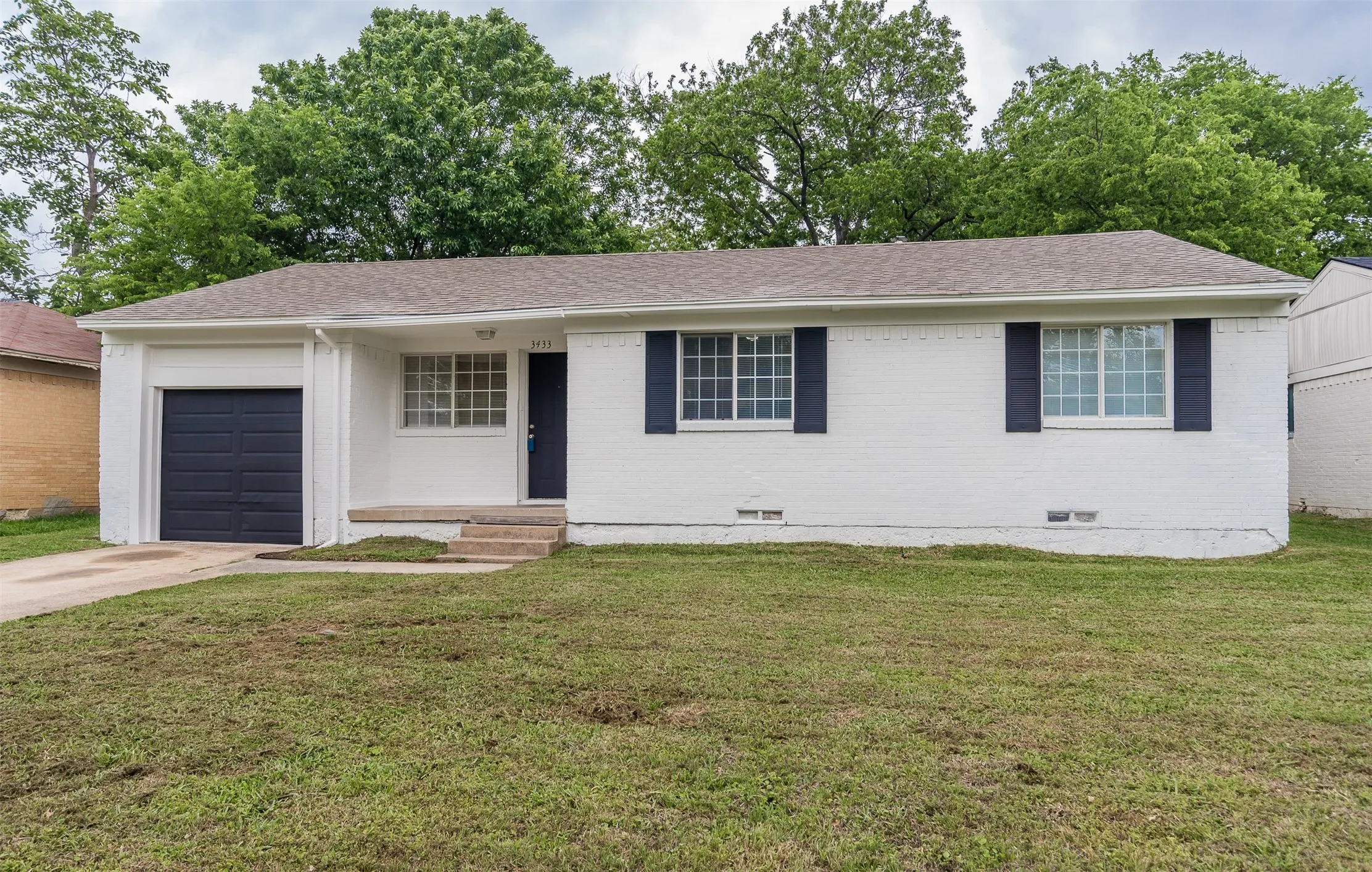 Single-story residence featuring a white brick exterior, dark blue shutters, and a matching dark blue garage door