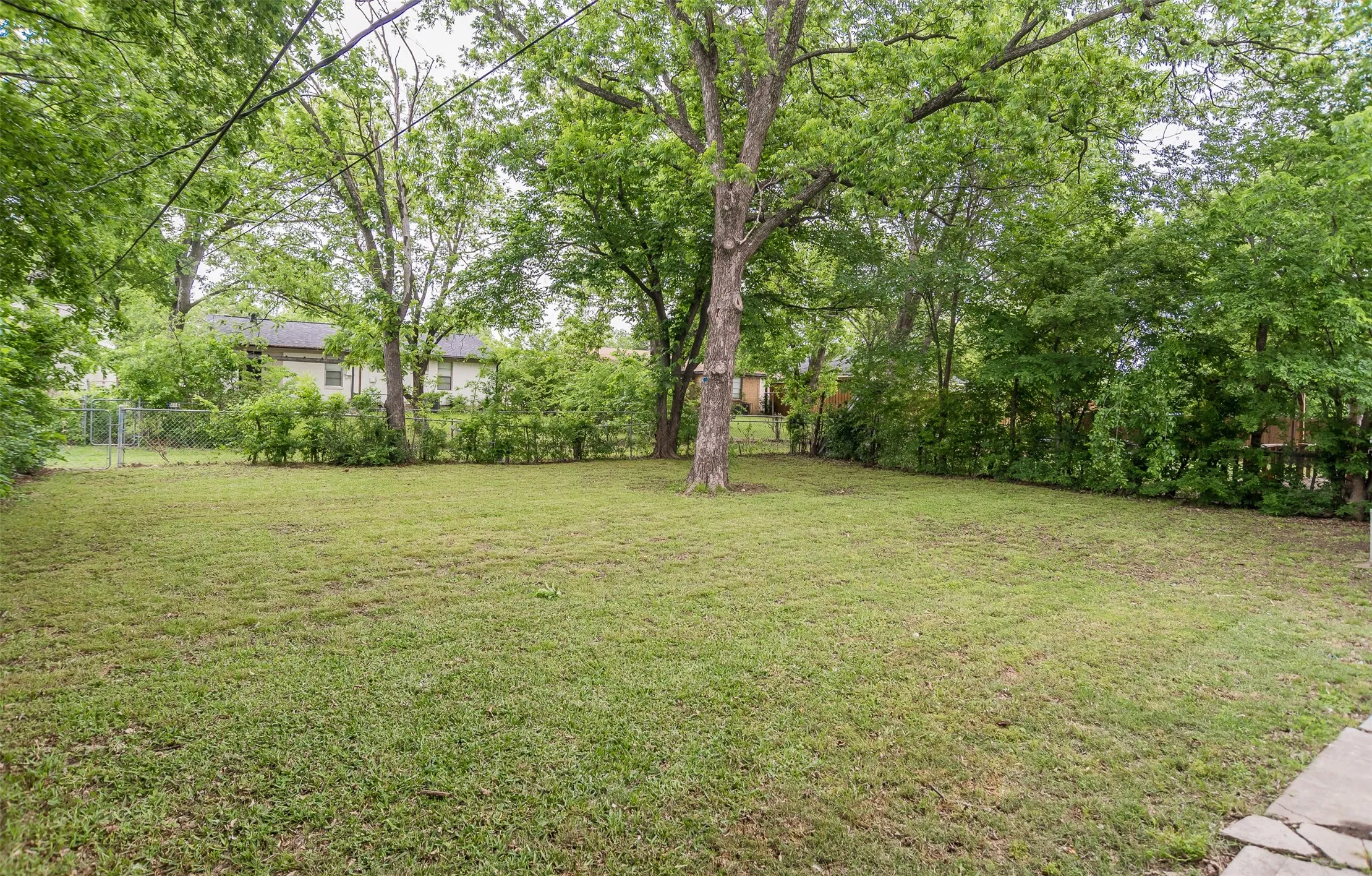 Expansive green lawn with mature trees and perimeter fencing