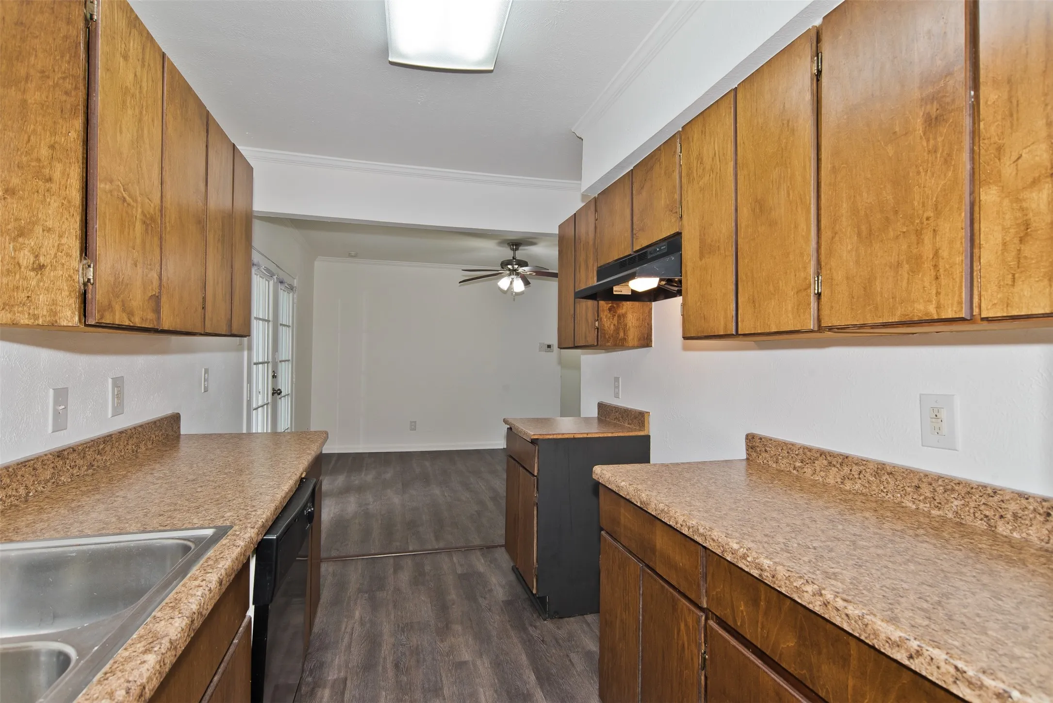 Kitchen featuring wood-finish cabinetry, speckled countertops, and a stainless steel sink
