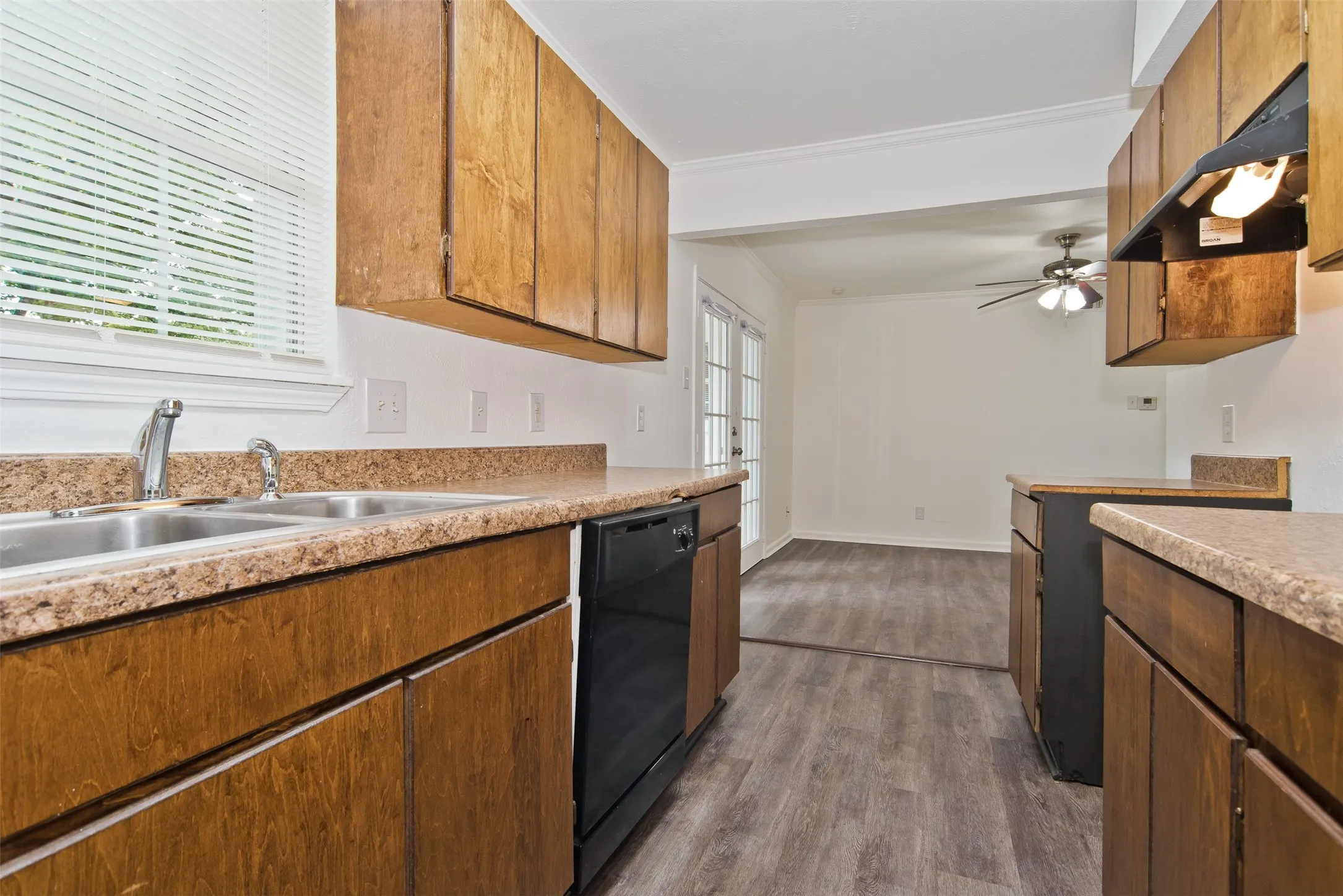 Kitchen featuring wood cabinetry, speckled countertops, a double basin stainless steel sink, and a black dishwasher