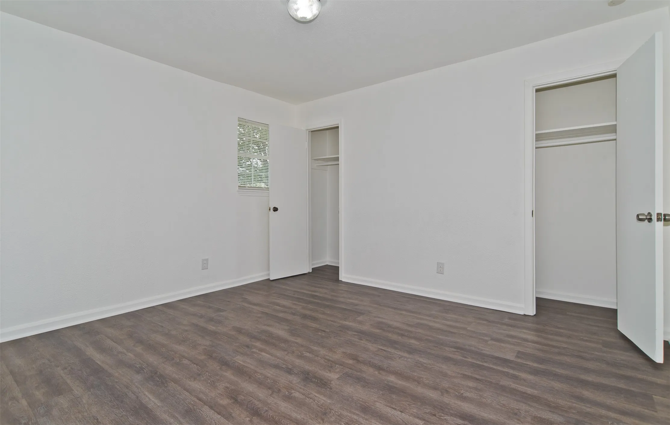 Spacious room featuring wood-finish flooring, crisp white walls, and bright white baseboards