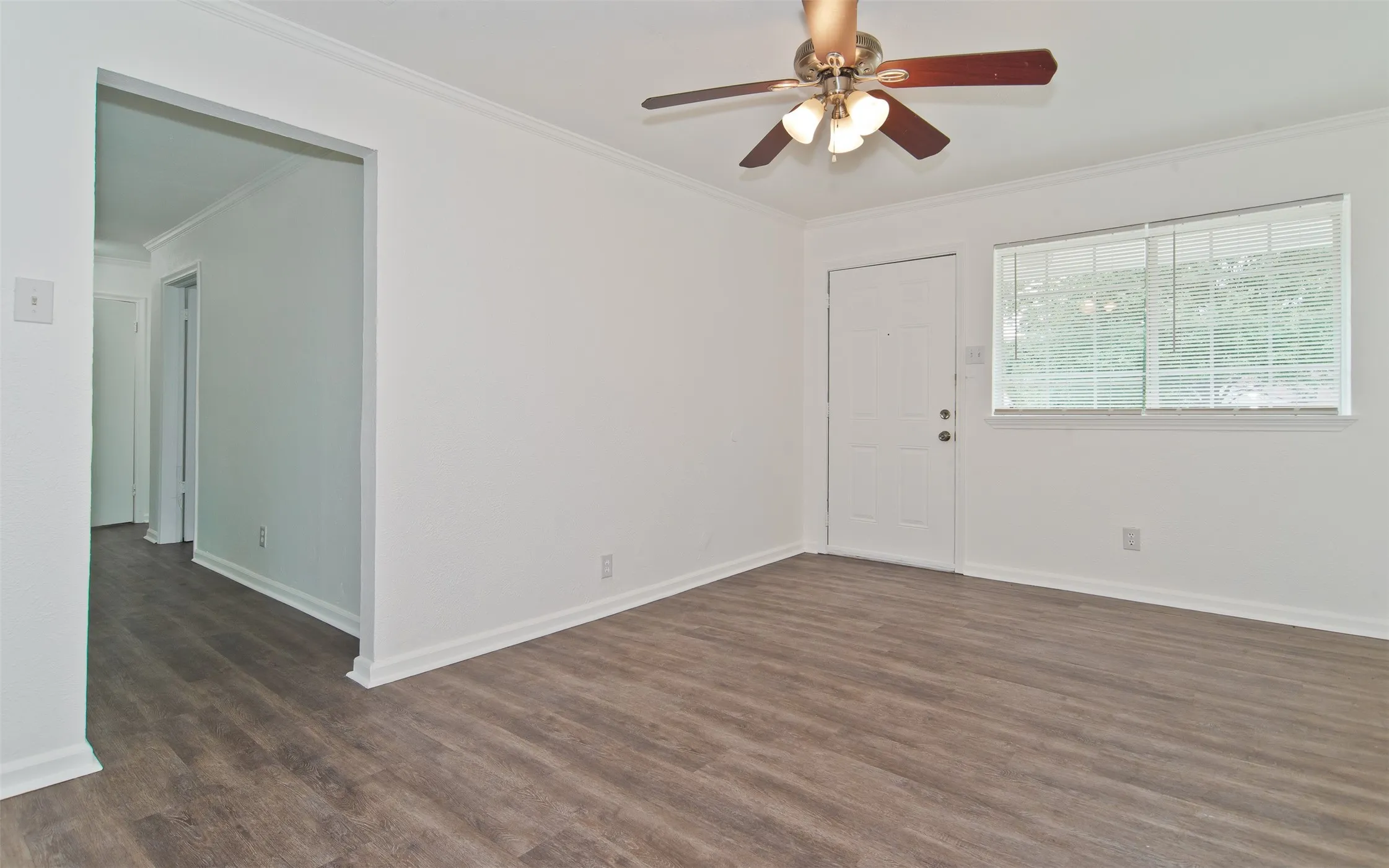 Living area featuring wood-finish flooring, white walls, and crown molding